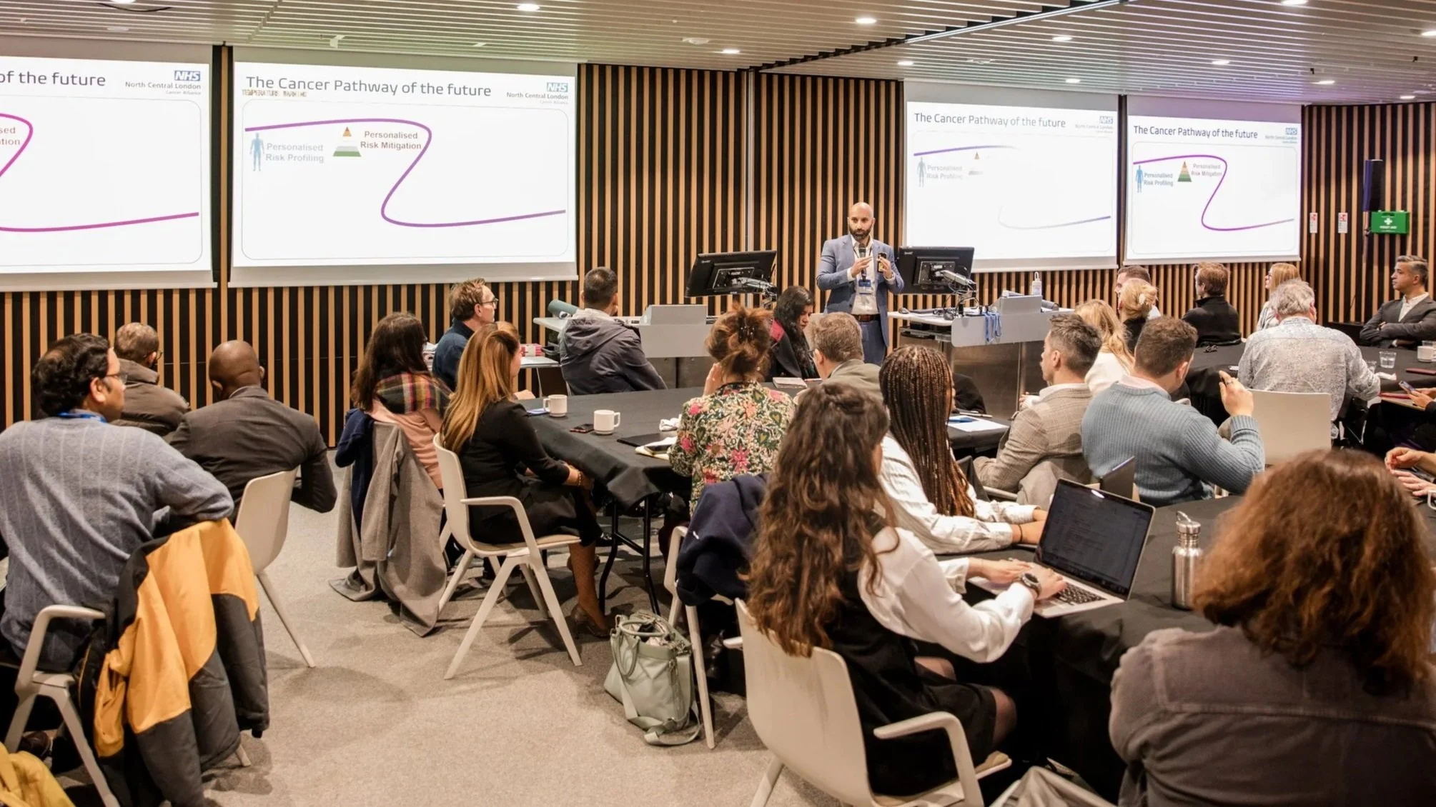 Ali Malik delivering the keynote in front of an audience