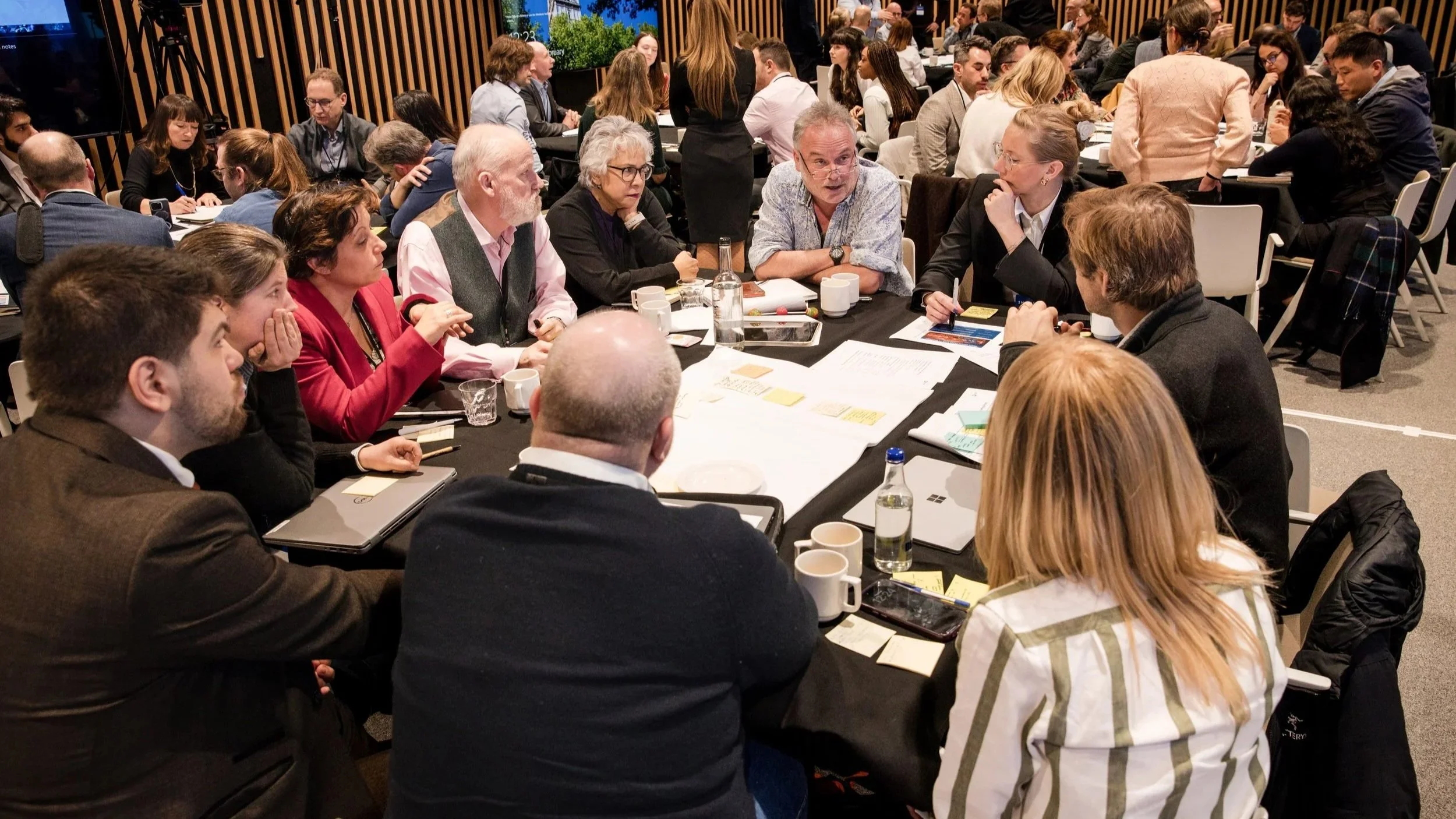 Groups of attendees have discussions around tables