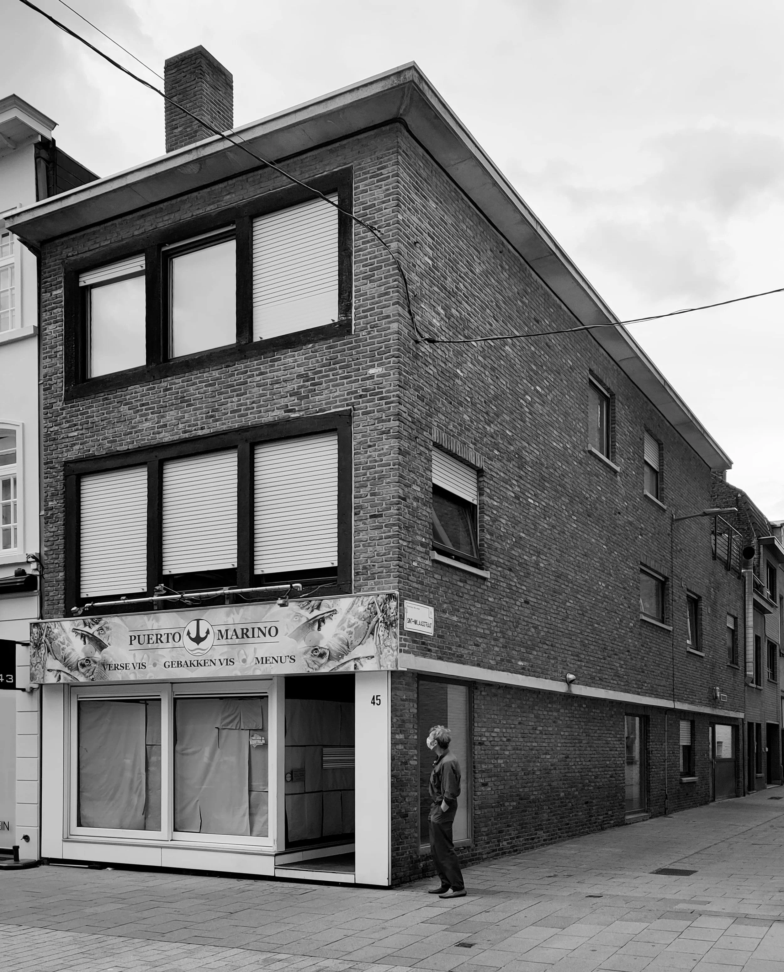 We zien een foto van een halfopen bebouwing met winkelruimte en appartementen in Kortrijk voor de start van de renovatiewerken.