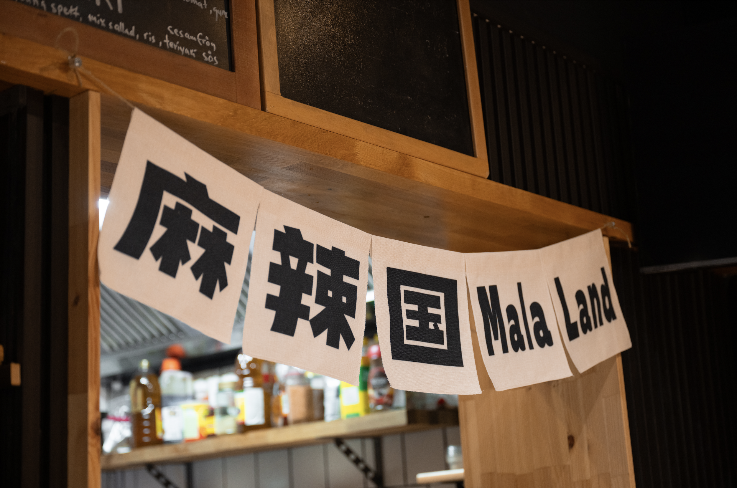 Text banner with 'Mala Land' in English and Chinese characters, hanging in a restaurant.