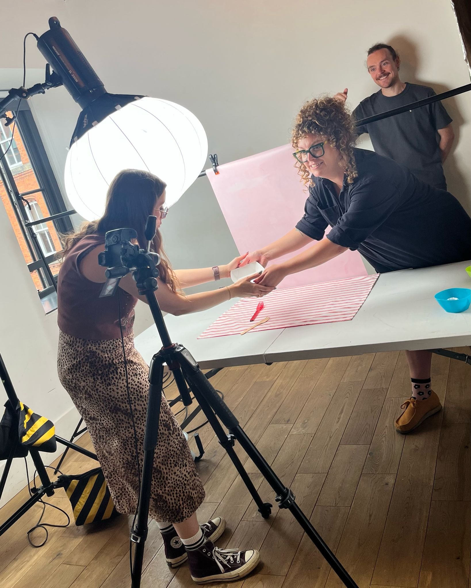 People taking part in a creative or photography project in a studio with lighting equipment and a backdrop.