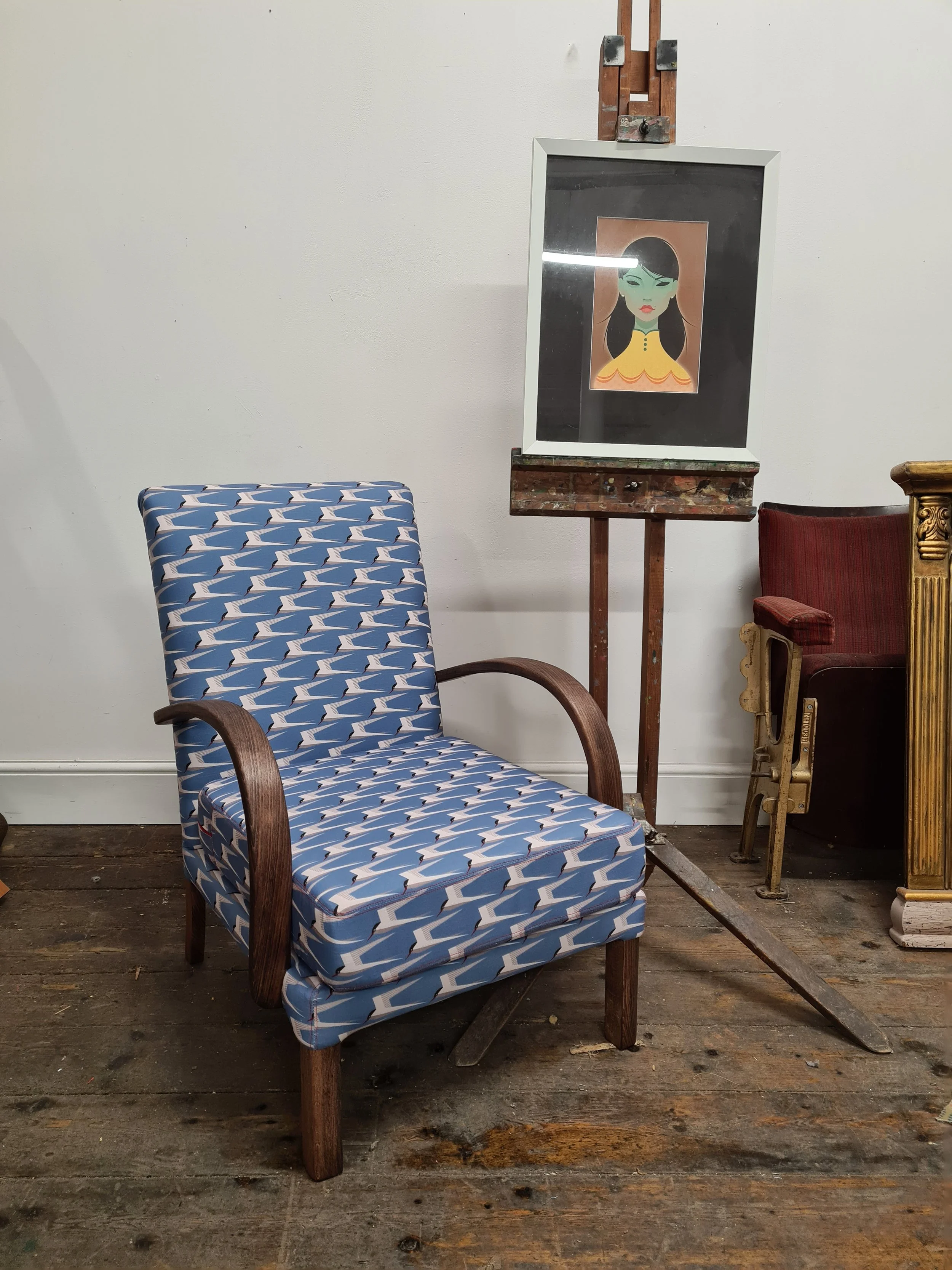 Vintage bentwood armchair reupholstered in blue bird fabric. easel in the background with stan chow print.
