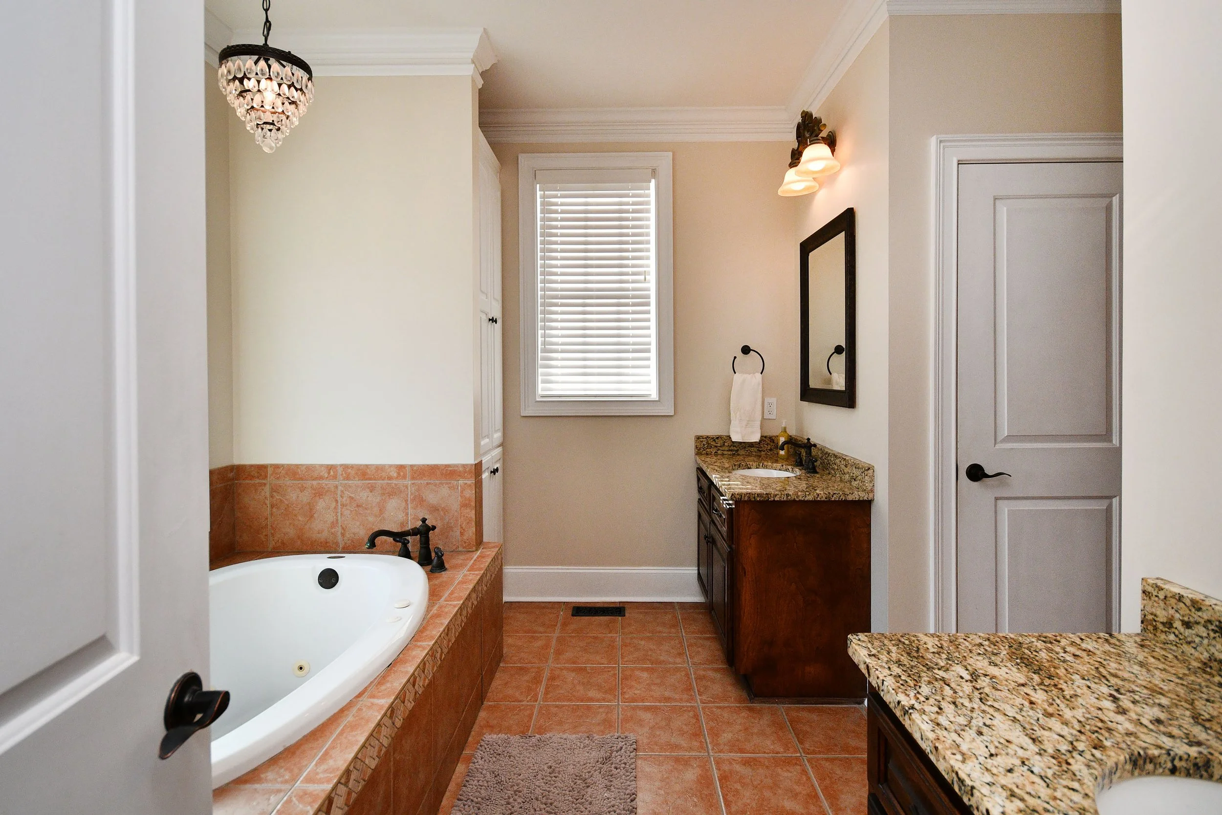 Bathroom with a corner bathtub, granite countertops, wooden cabinets, a mirror, towel rings, a sink, and a window with blinds. Home for sale in Greenville, SC. Master on Main Level. 4 Bedroom home for sale. Upscale Community. 
