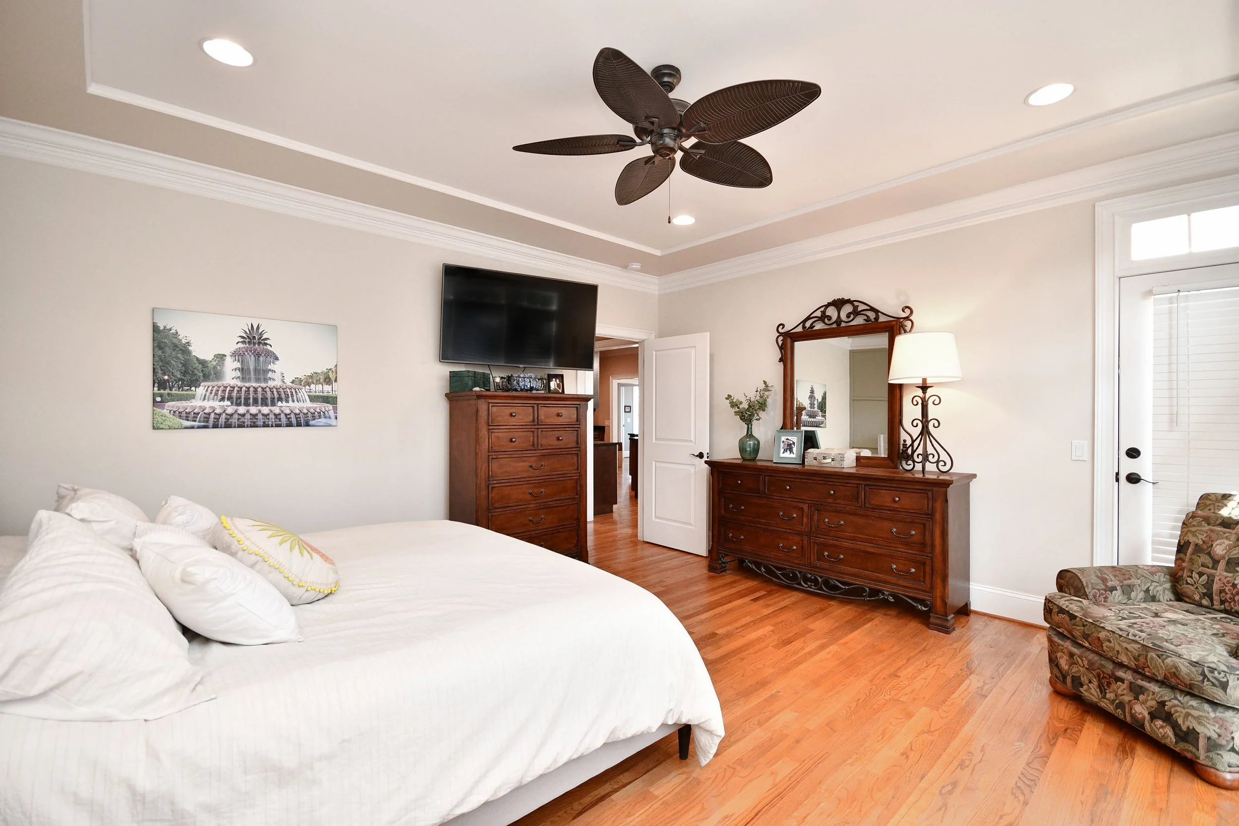 A bedroom with a large bed, wooden furniture, a ceiling fan, and a door leading outside. Home for sale in Greenville, SC. Master on Main Level. 4 Bedroom home for sale. Upscale Community. 