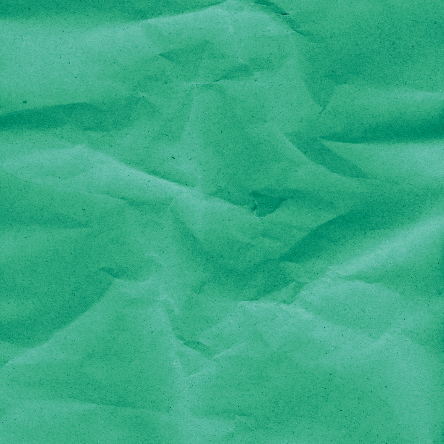 Close-up of crumpled green paper with irregular folds and varying shades of green.