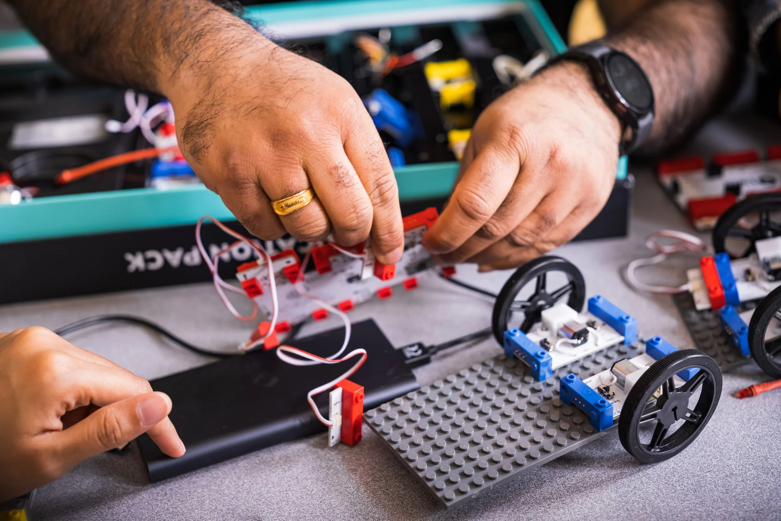 Hands assembling robot from electronics kit, CSR and social value campaign for LetsLocalise by story agency STORO