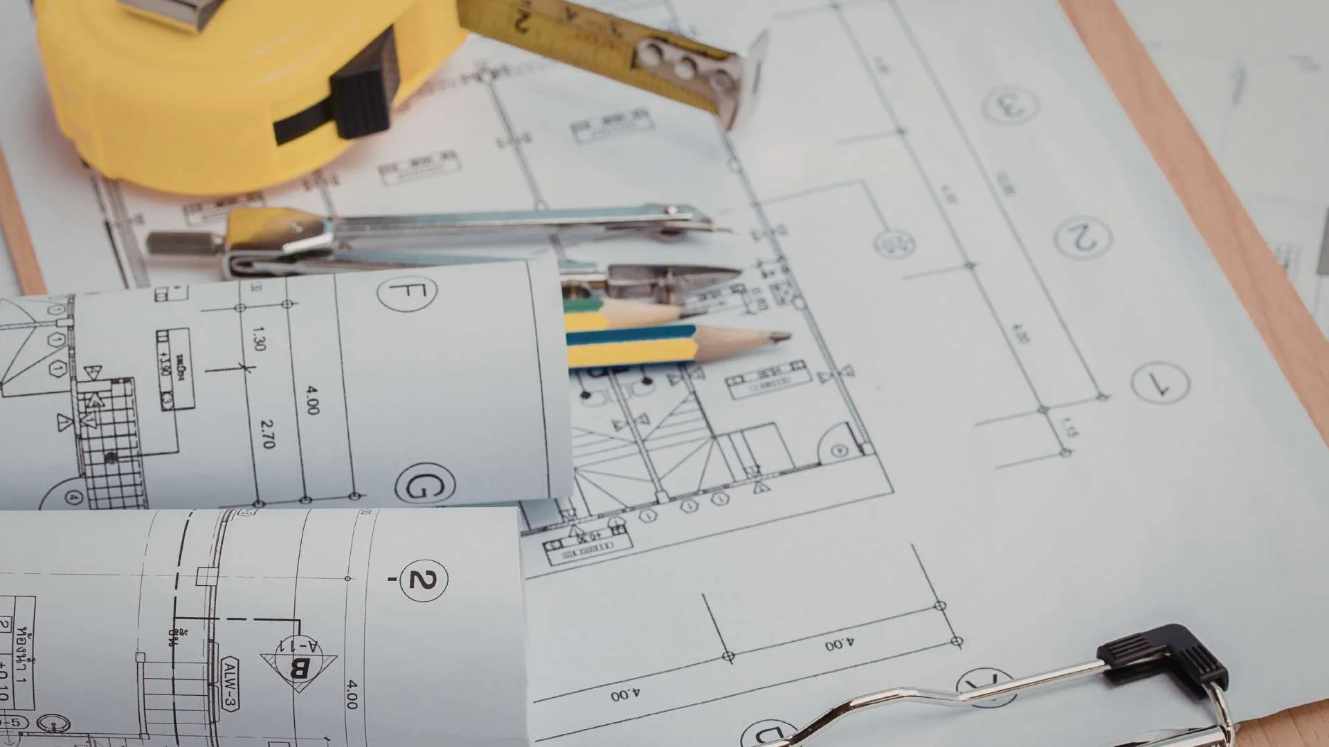Blueprints and industrial planning documents with measuring tools and drafting equipment representing proactive abatement planning before facility shutdowns and turnarounds