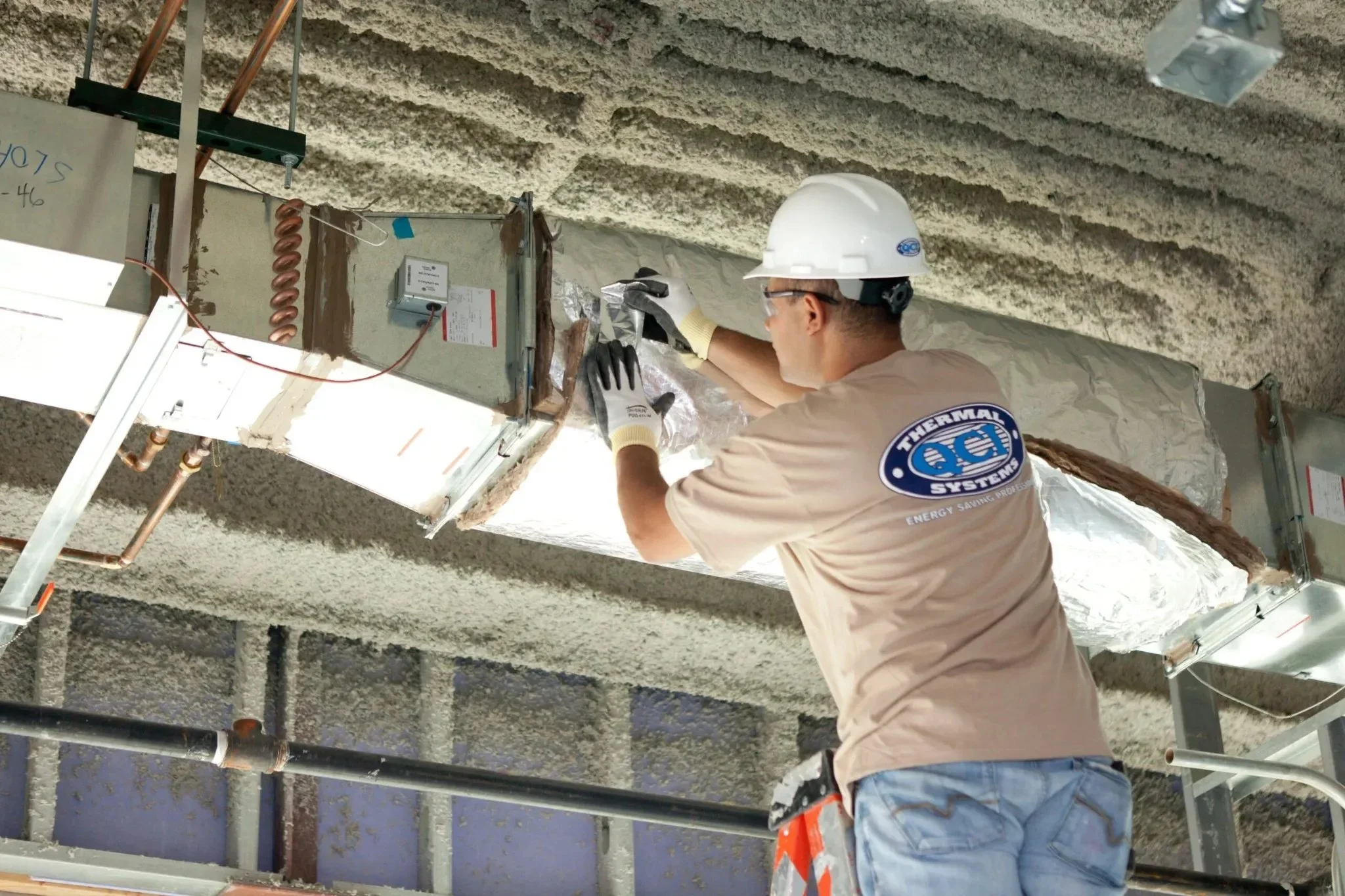 QCI Thermal Systems installer performing HVAC ductwork insulation installation inside a commercial building.