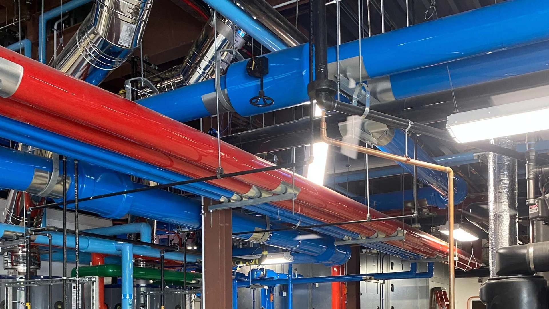 Insulated mechanical piping system in a facility mechanical room demonstrating proper insulation on heating and cooling lines