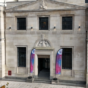Historic stone building with two banners at the entrance and the word "UniLife" above the doorway.