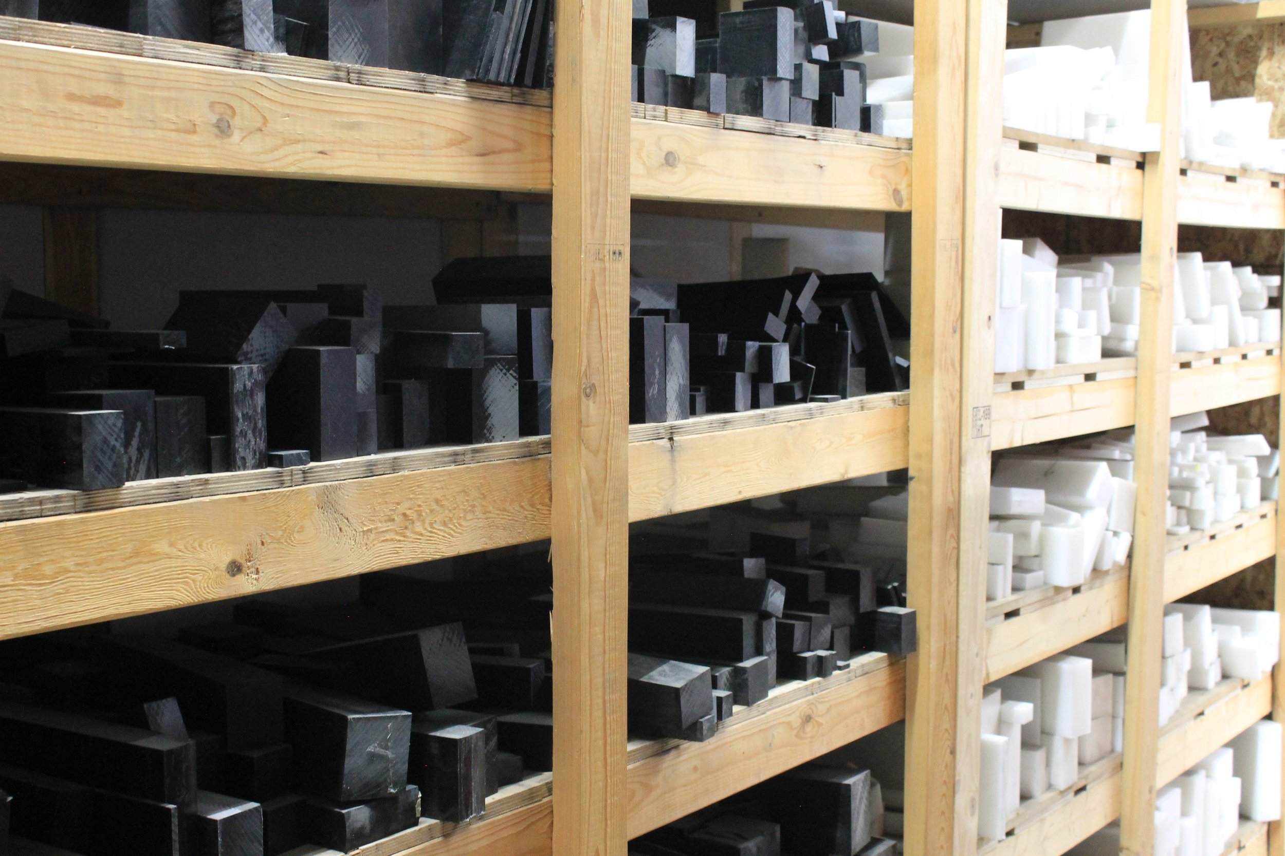 Wooden shelves stocked with black and white plastic or resin pieces in various shapes and sizes.