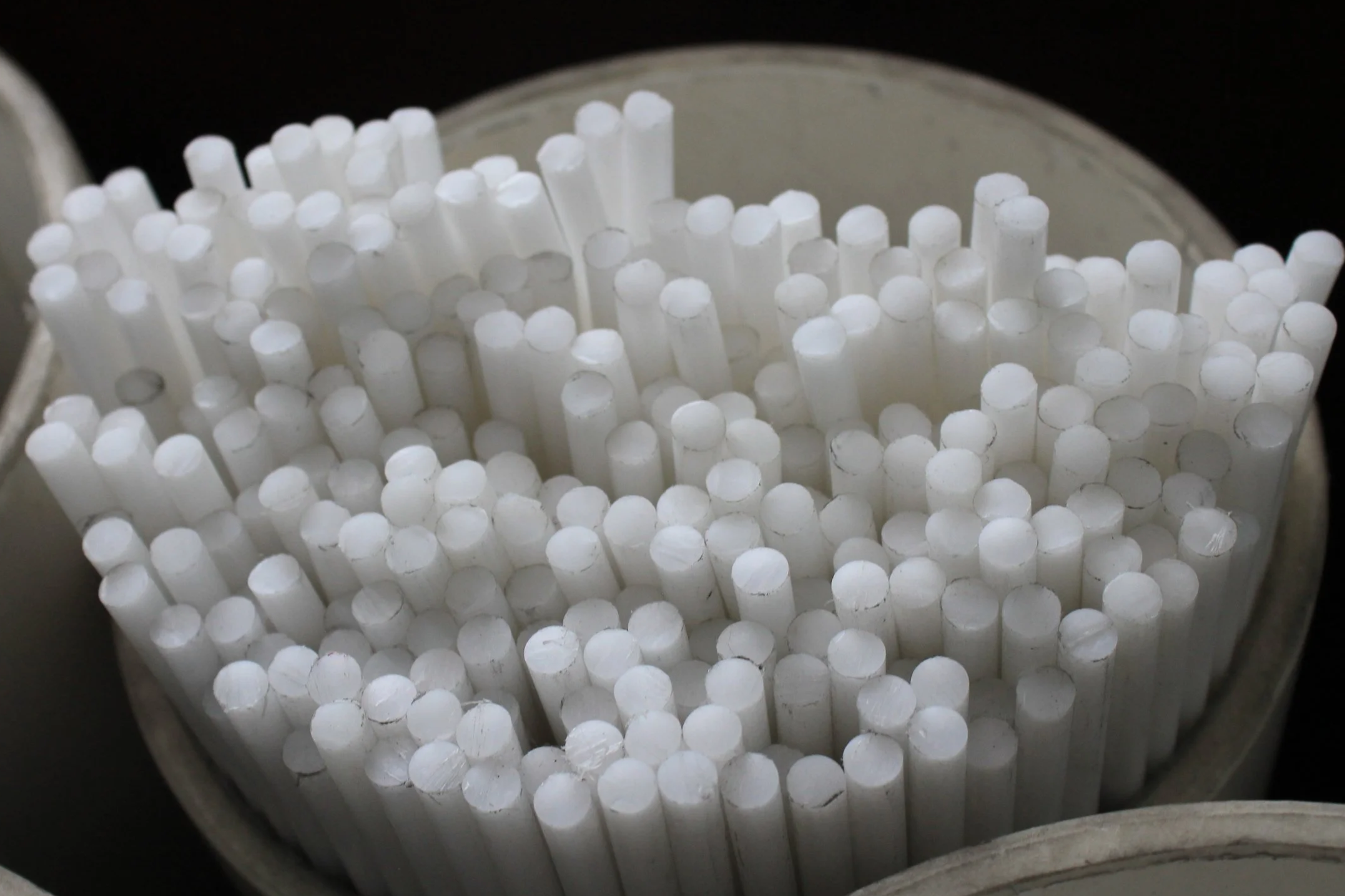 Close-up of numerous white cylindrical sticks in a container.