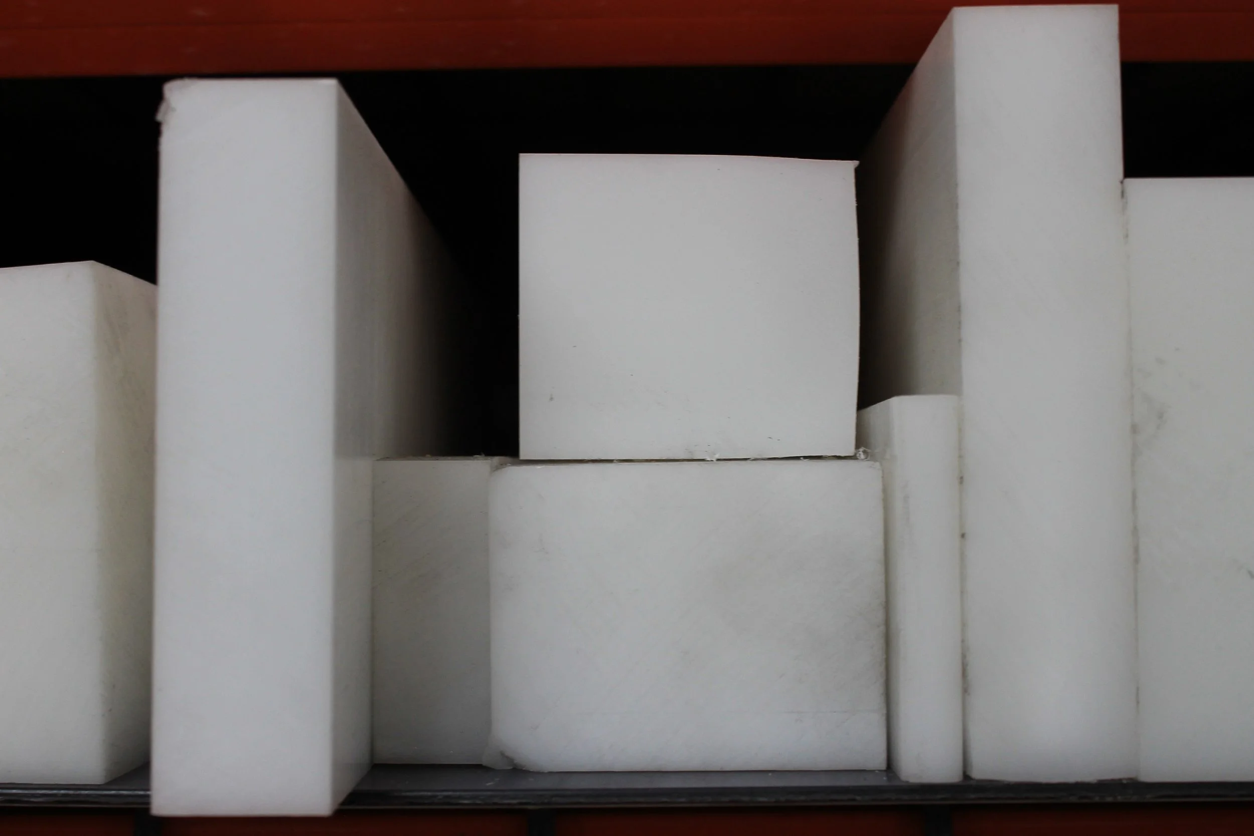 Close-up of white rectangular blocks arranged on a shelf, with a dark background and a red edge at the top.