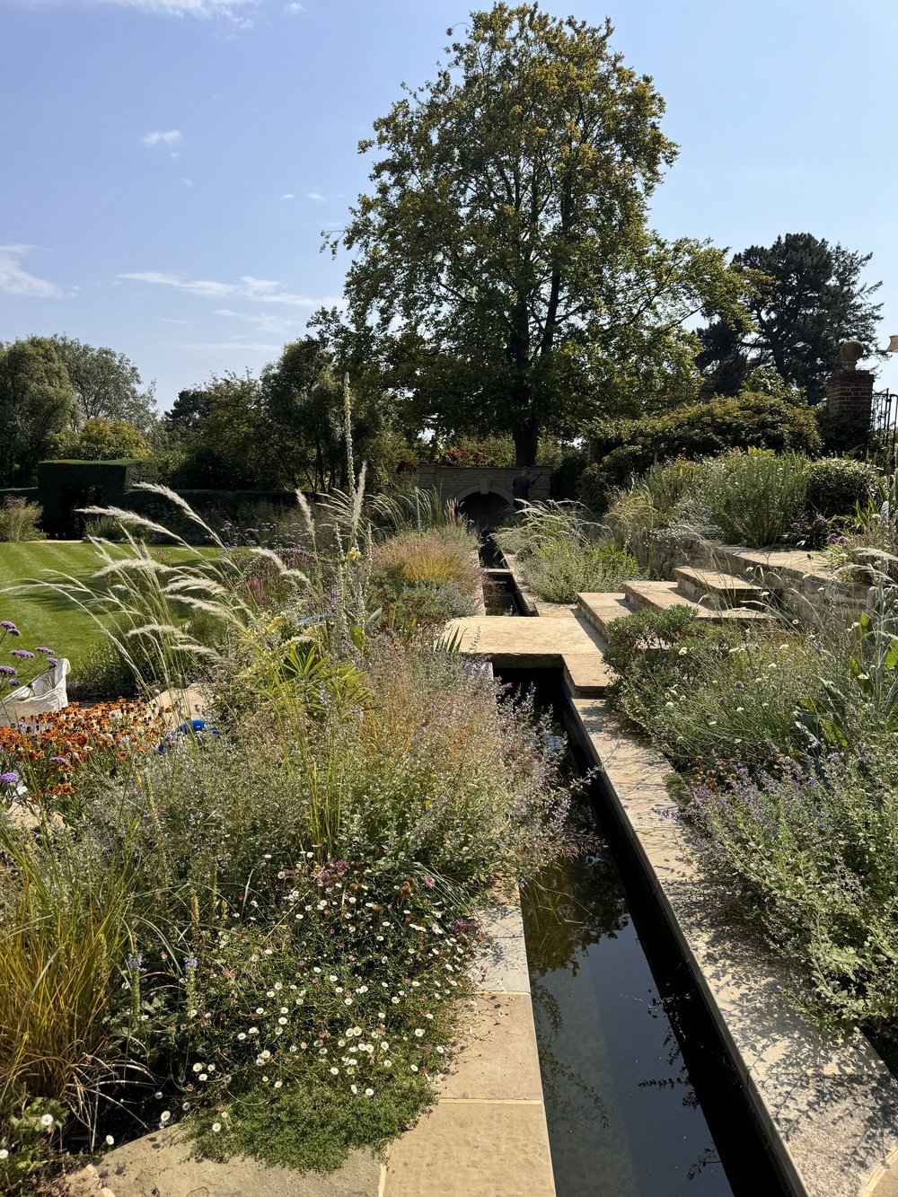 Ornamental grasses and perennials beside a stone rill