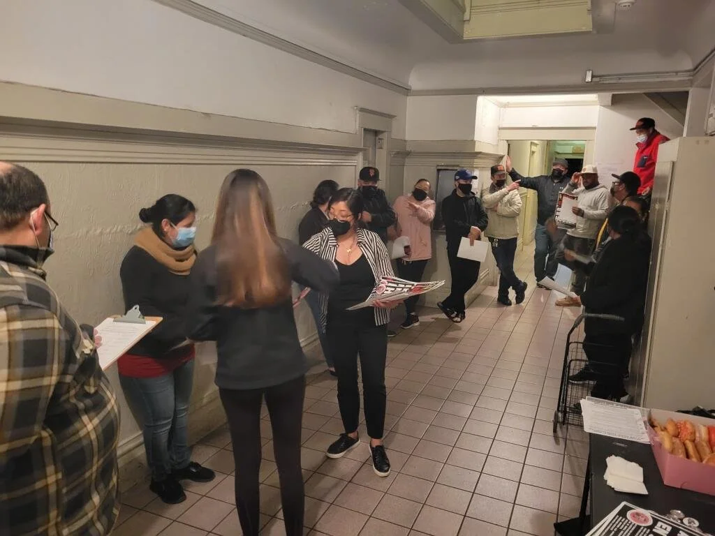 Scenic view of mountains in the distance around a body of water with trees in the foreground and a building on the right.