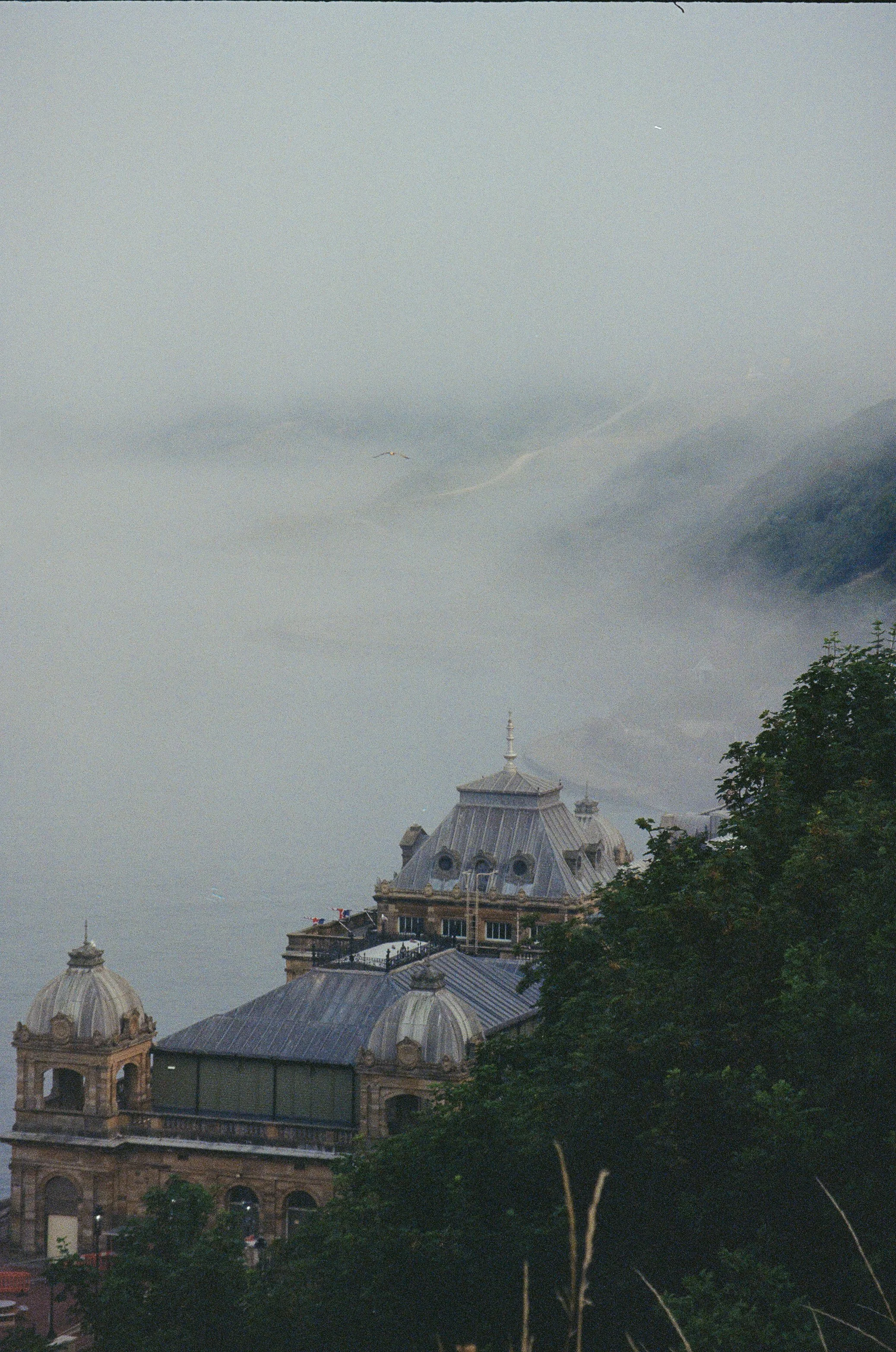 Old building with ornate dome roofs and spires in foggy coastal landscape