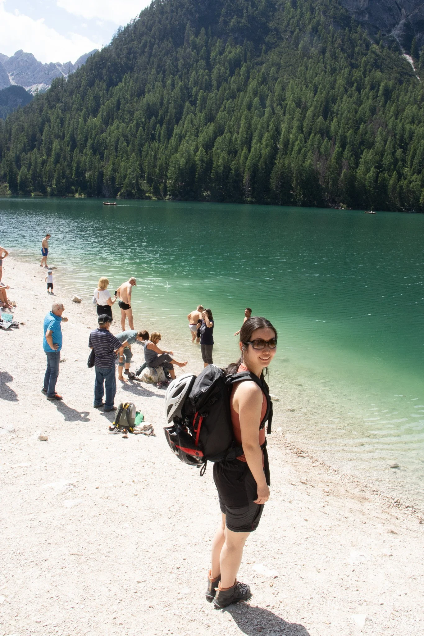 People enjoying a day by a mountain lake with clear waters, surrounded by pine forests.