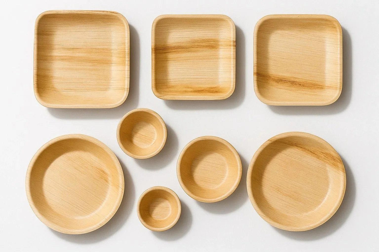 Set of seven areca bowls and plates of various sizes arranged on a white surface.