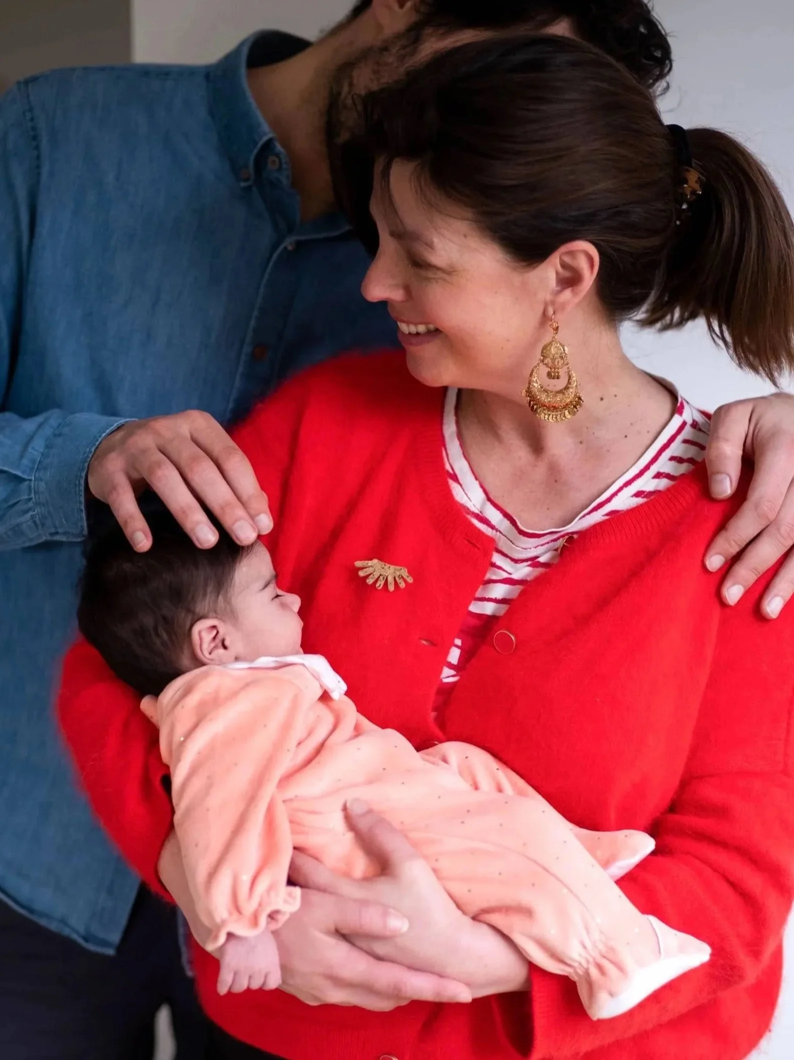 Une femme souriante qui tient un bébé dans ses bras lors d'une réunion ou d'un moment d'affection.