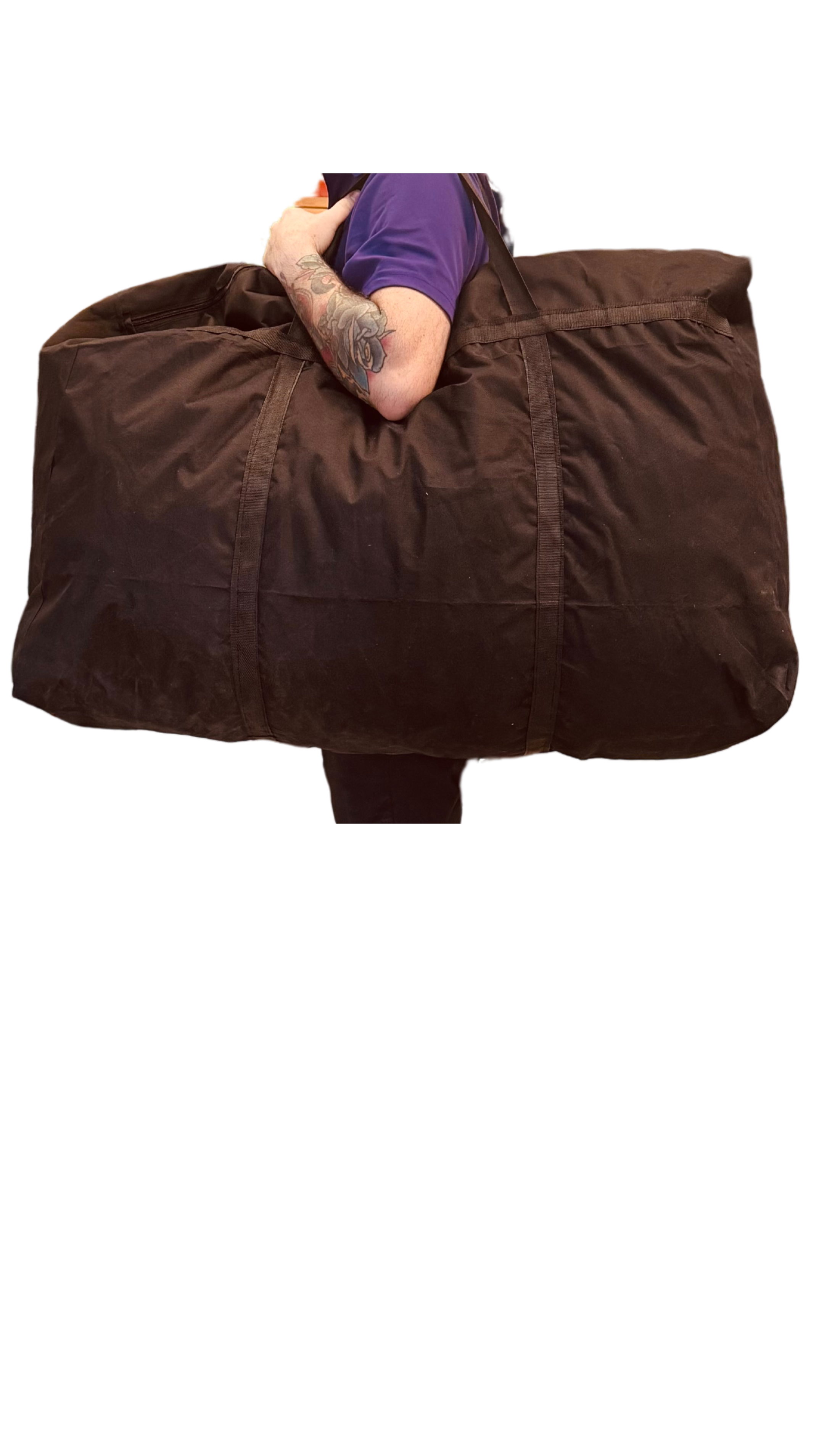 Person carrying a large brown duffel bag over their shoulder, wearing a blue shirt, with tattoos on their left arm.