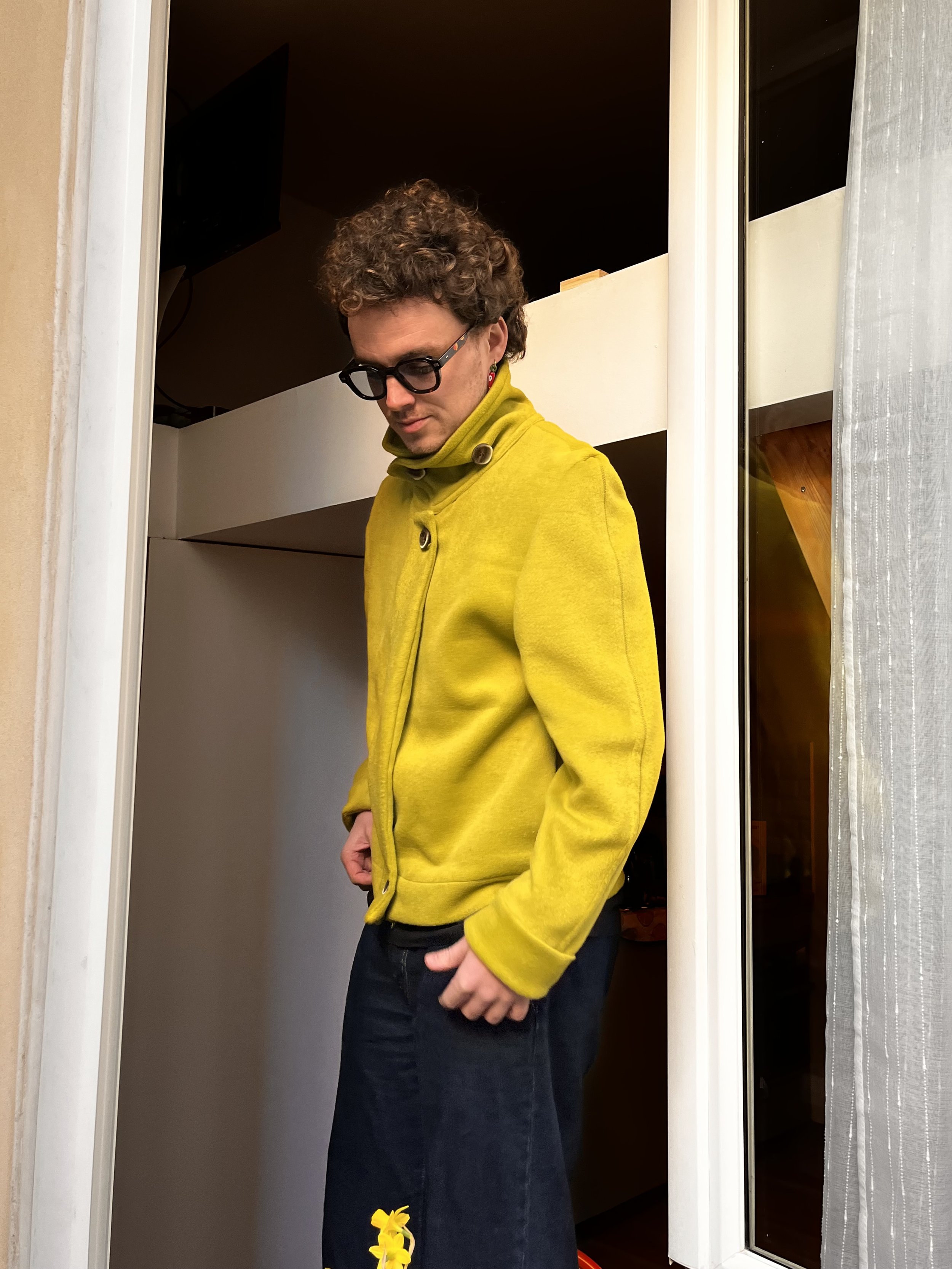 jeune Homme pris en photo à la fenêtre d’un appartement parisien, portant une veste vert anis, cousue main