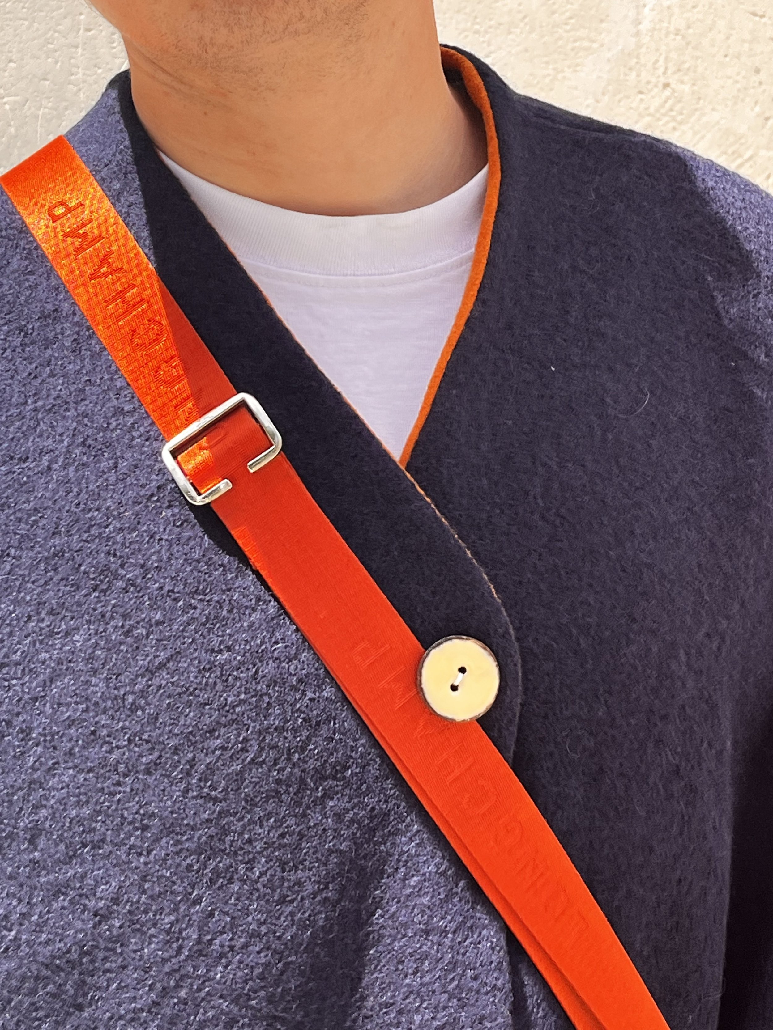 Photos de près d’un gilet en laine bleu, avec un bouton en ivoire beige