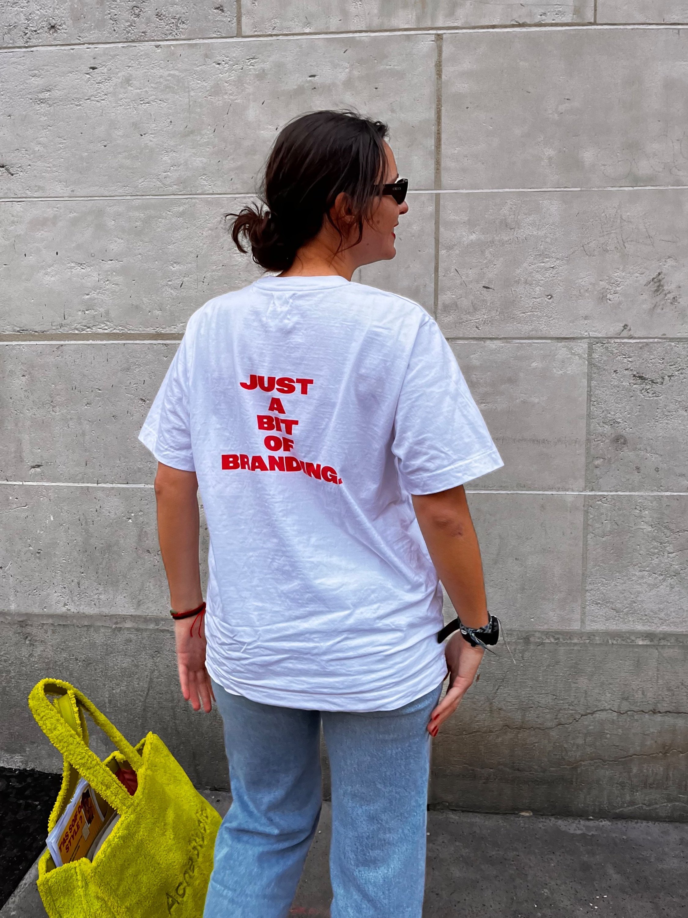 Mannequin féminin de dos dans les rues parisiennes, portant un t-shirt blanc avec écriture orange soutenu
