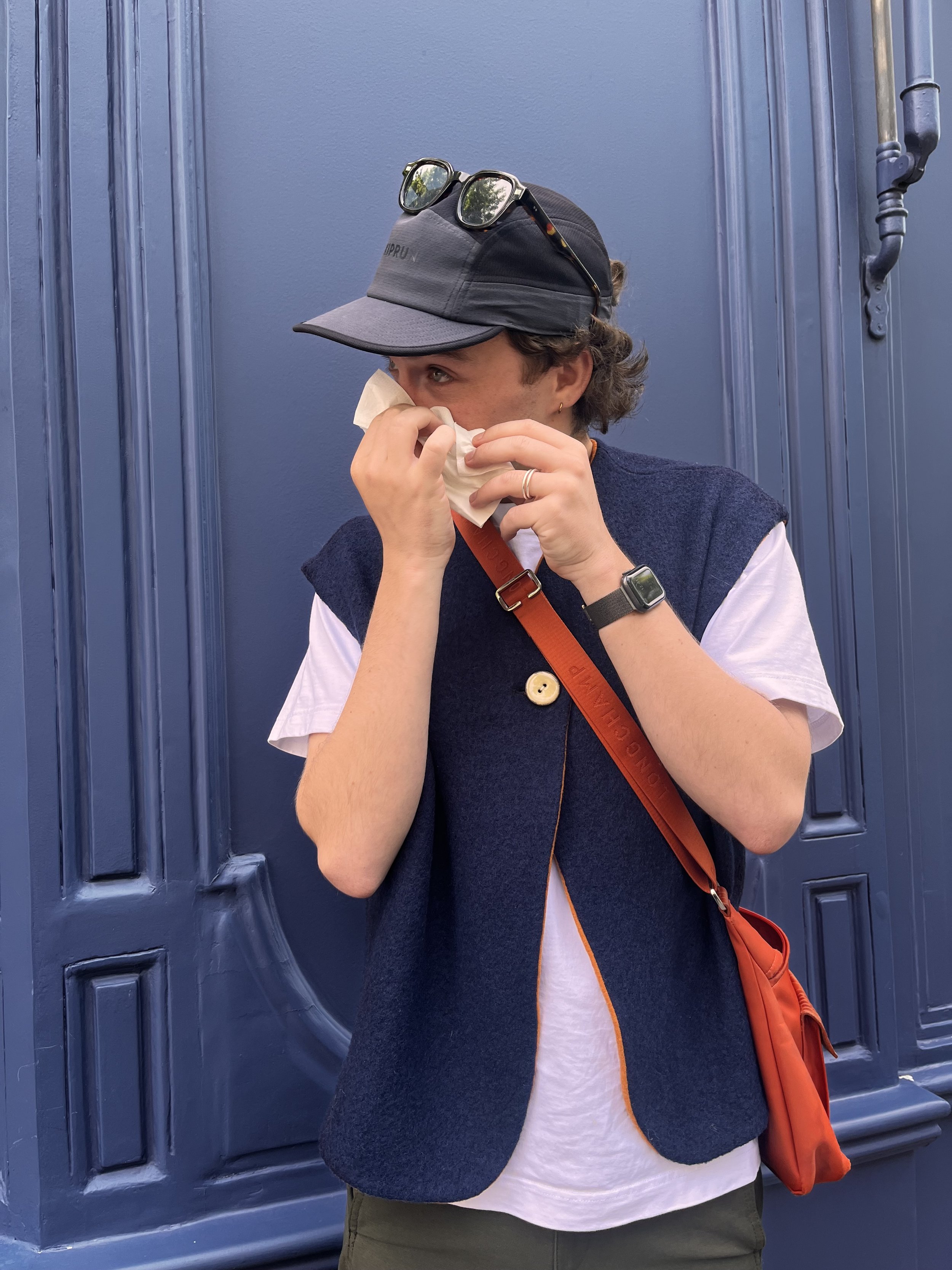 Photo d’un jeune homme se mouchant et portant un gilet en laine bleu