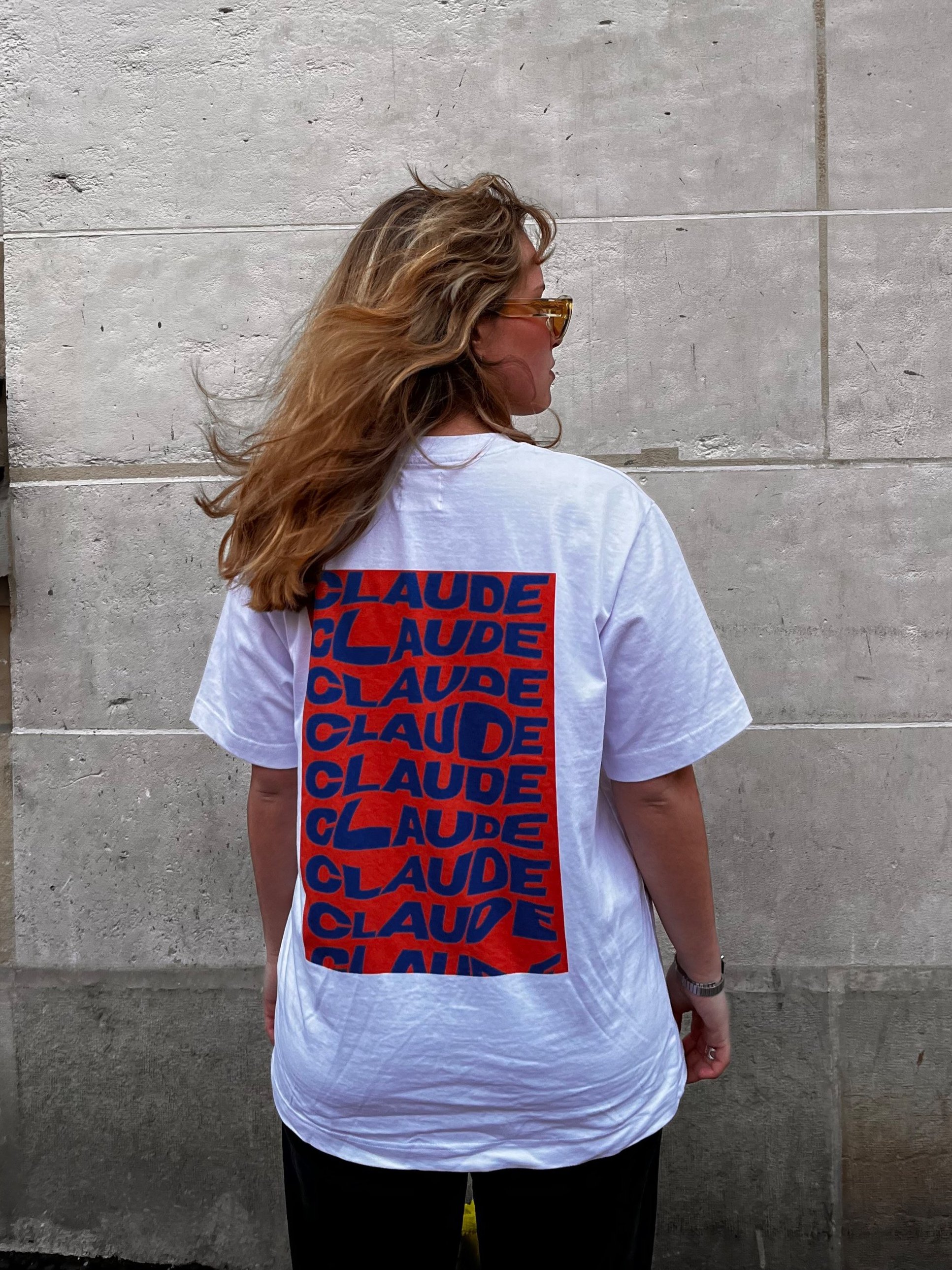 Mannequin féminin arborant un t-shirt Claude de dos dans les rues parisiennes