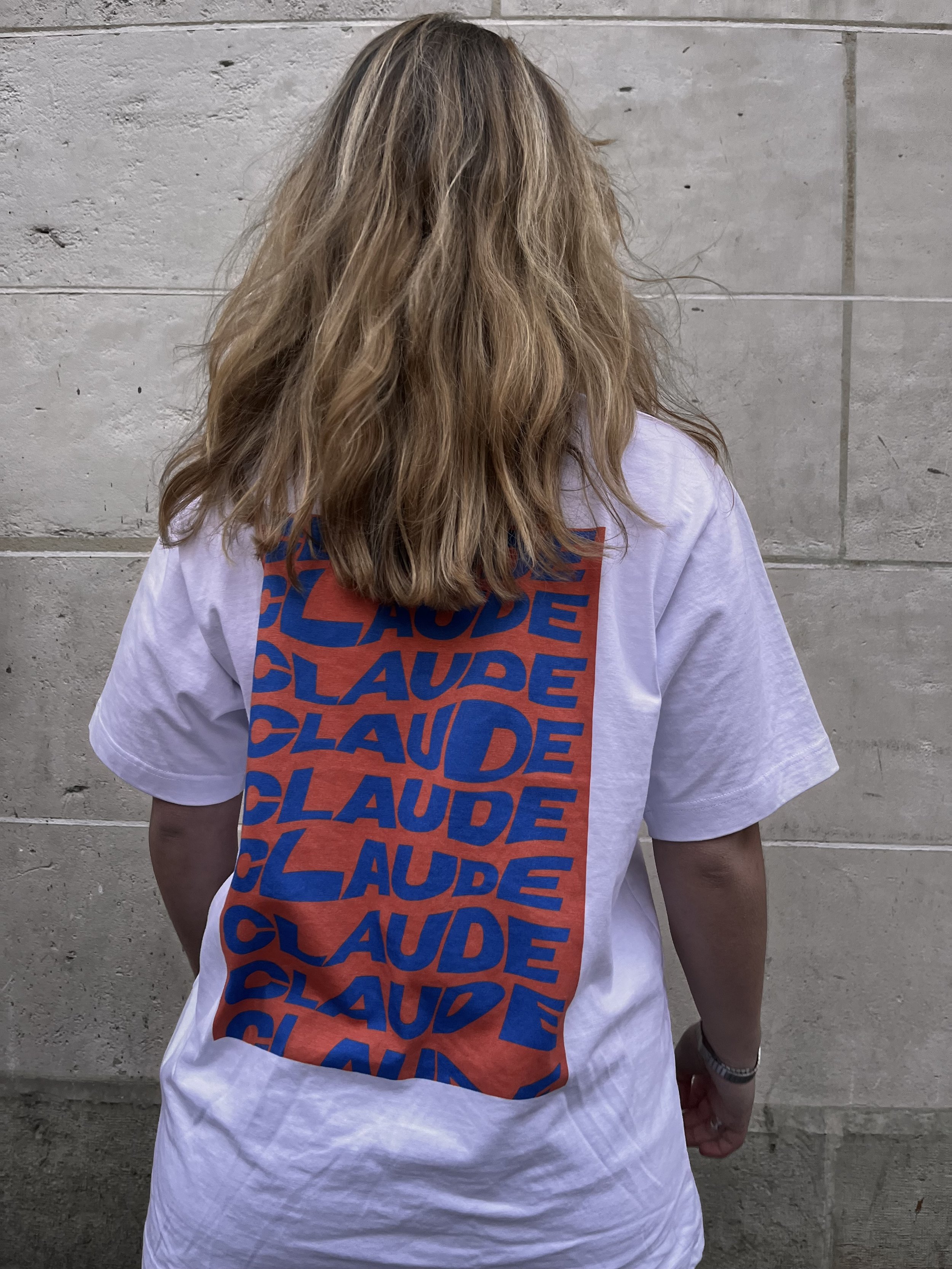 Femme blonde photographiée de dos portant le t-shirt MOUVEMENT BY CLAUDE