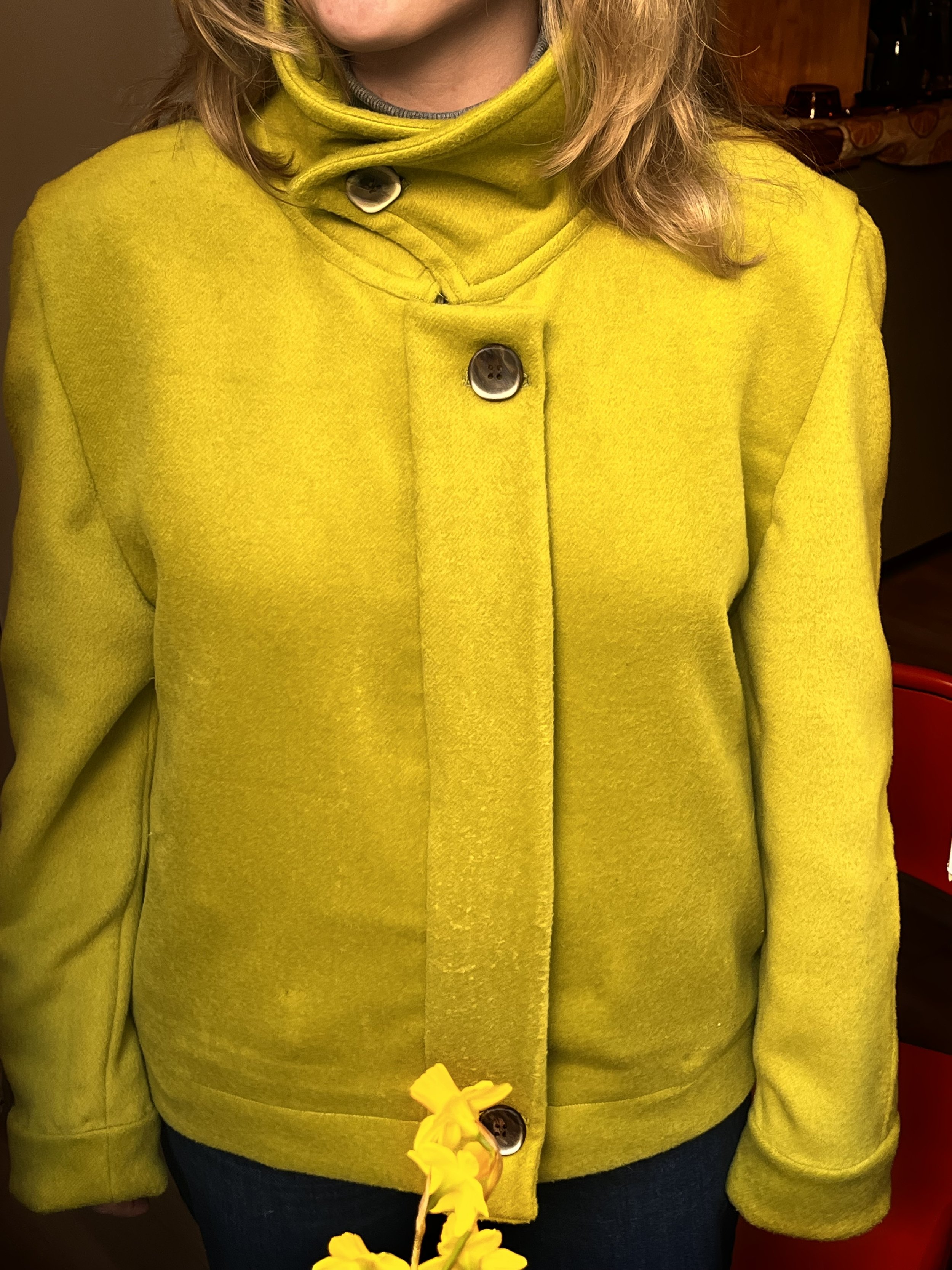 Photo prise d’une veste cousue à la main, de couleur vert anis avec un col montant et une patte de boutonnage