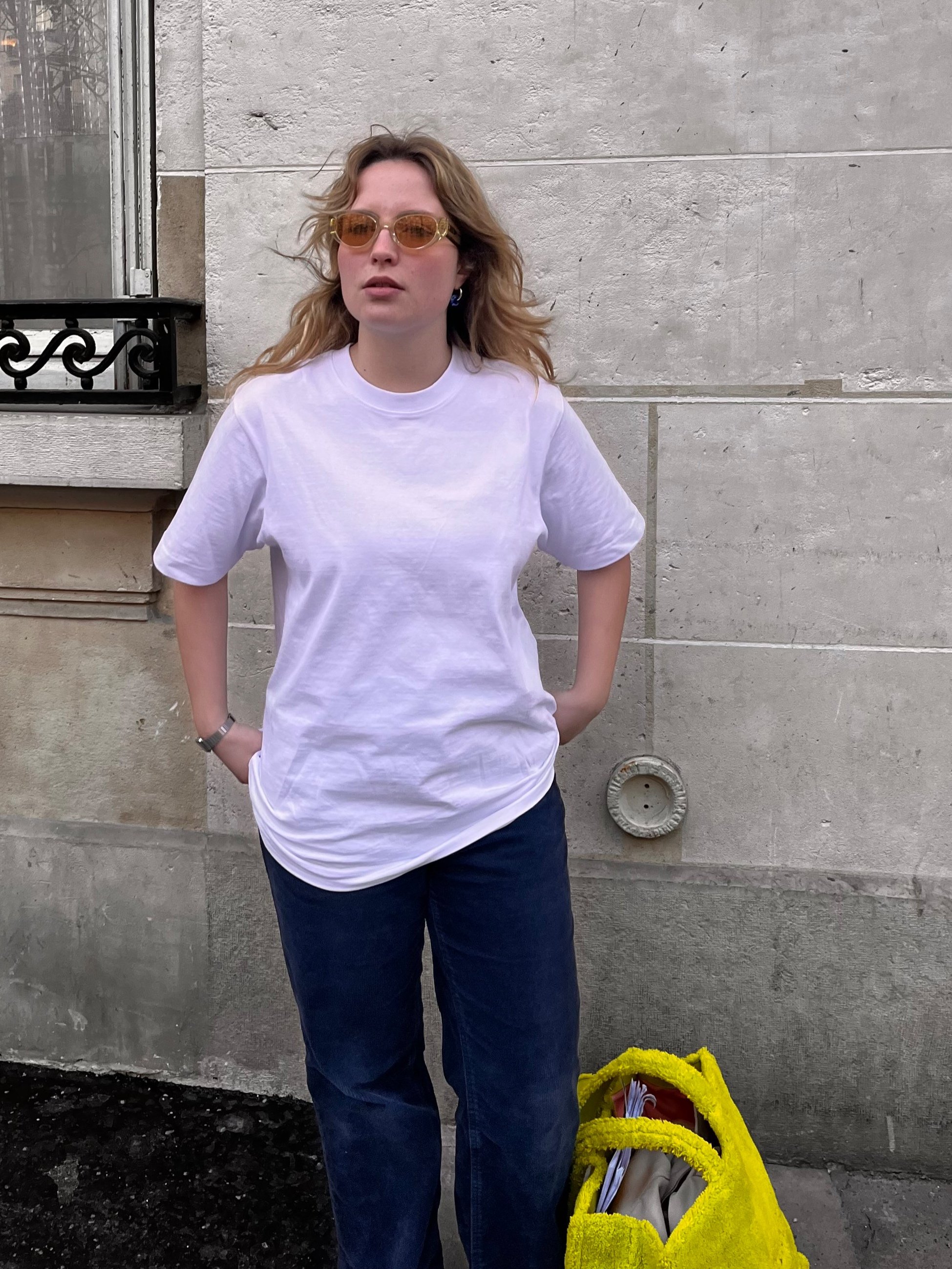 Mannequin féminin photographiée dans les rues parisiennes, arborant un t-shirt blanc Claude by Claude
