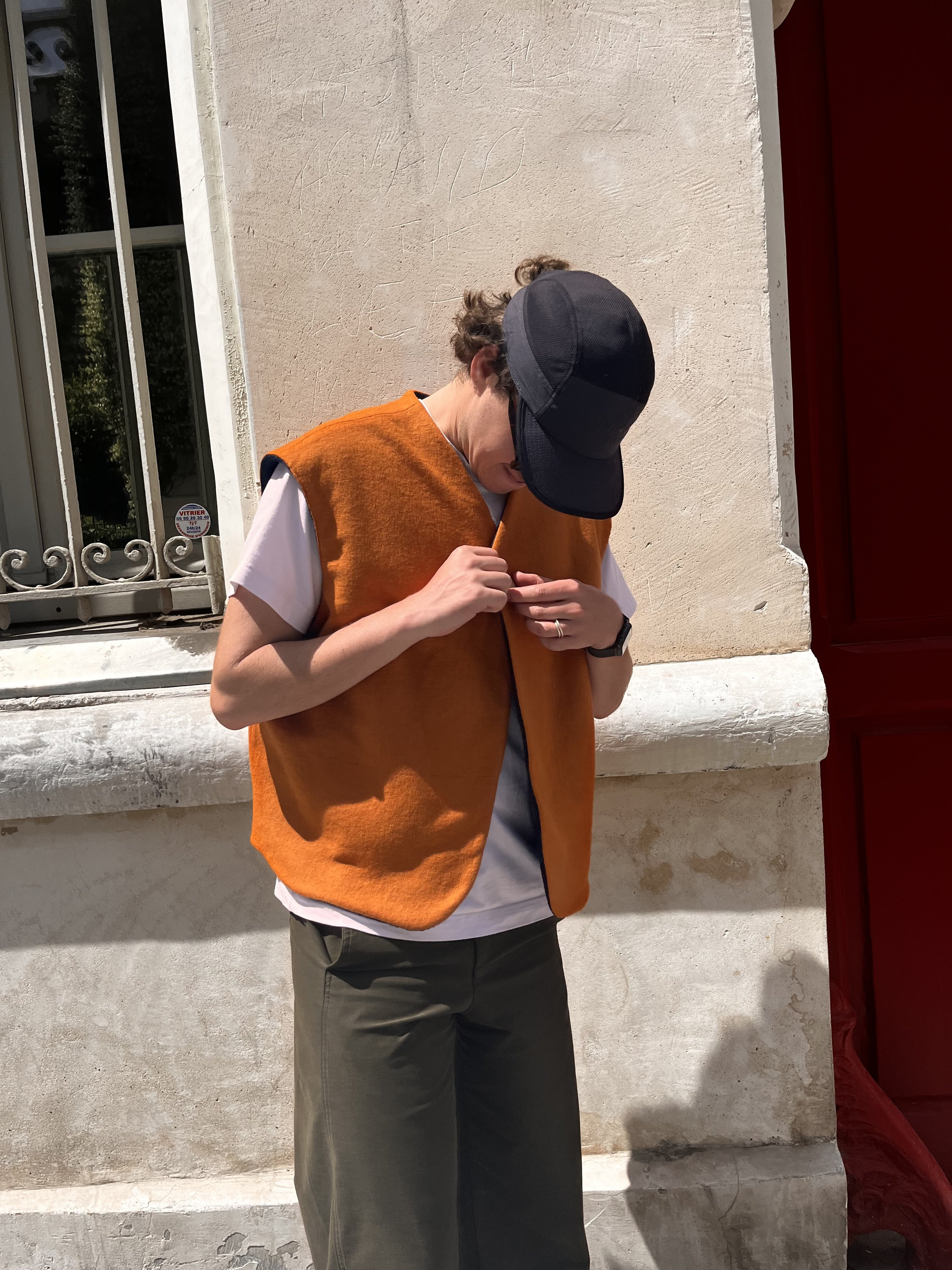 Photo d’un jeune homme fermant un gilet sans manche en laine orange