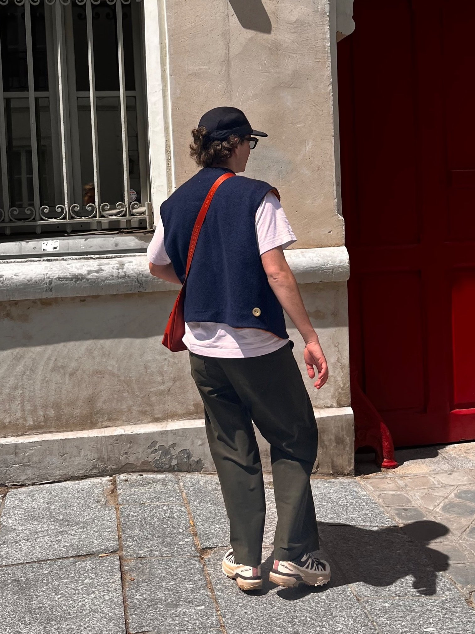 Photo d’un jeune homme de dos dans les rues parisiennes, portant un gilet en laine bleue