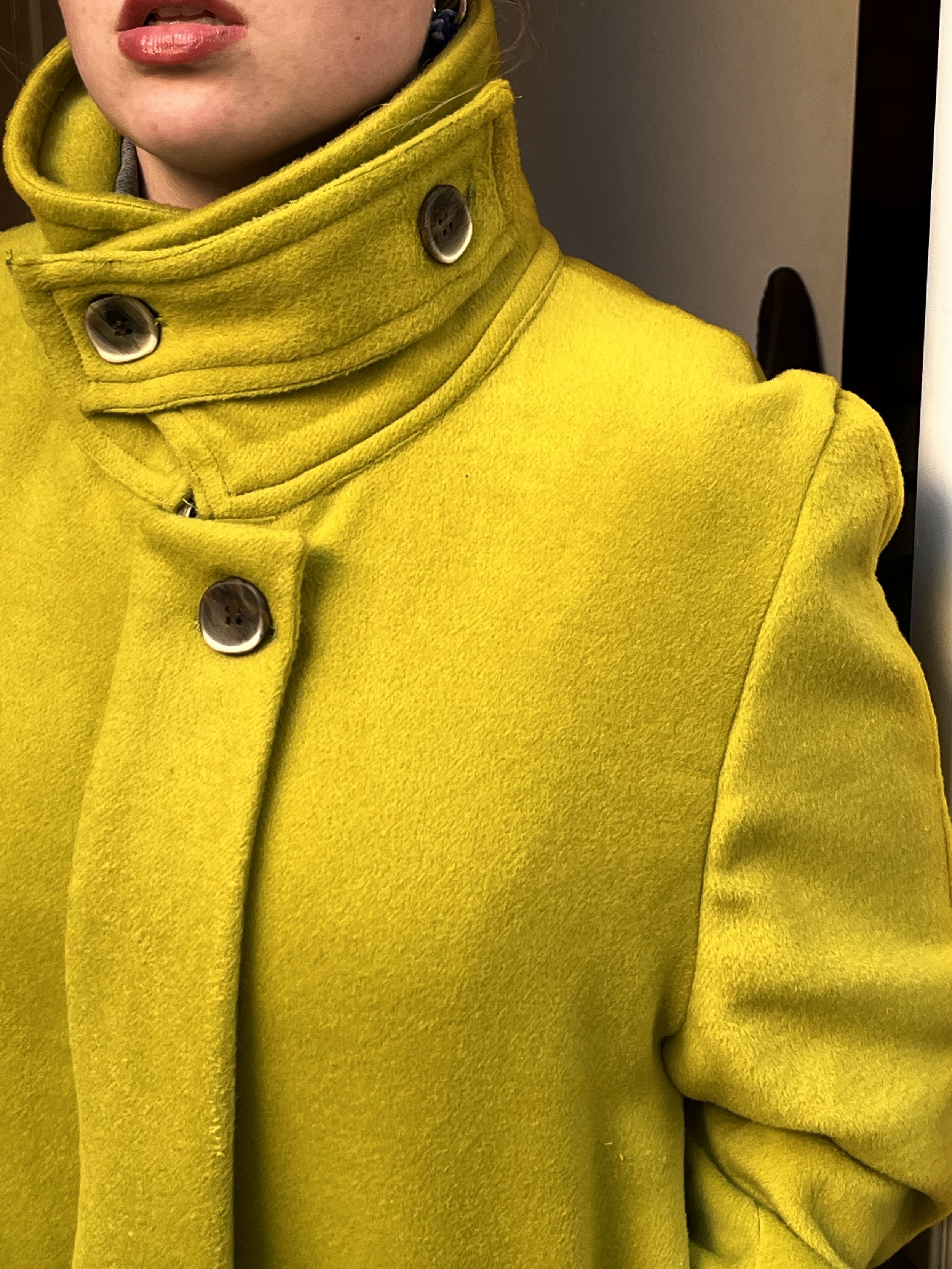 Zoom sur les détails d’un col de veste en laine portée par une jeune femme aux lèvres pulpeuses