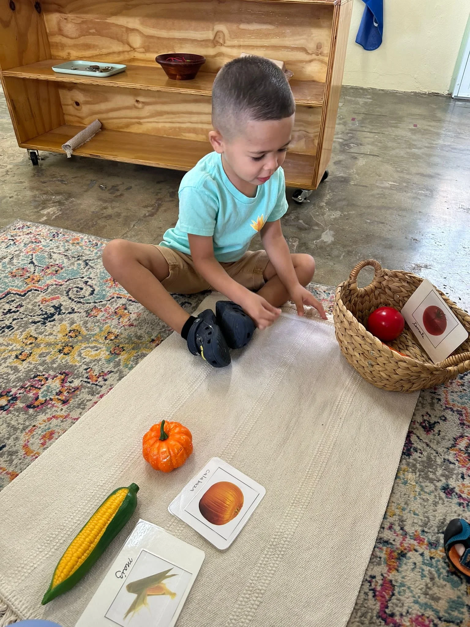 niño sentando en un tapete con objetos