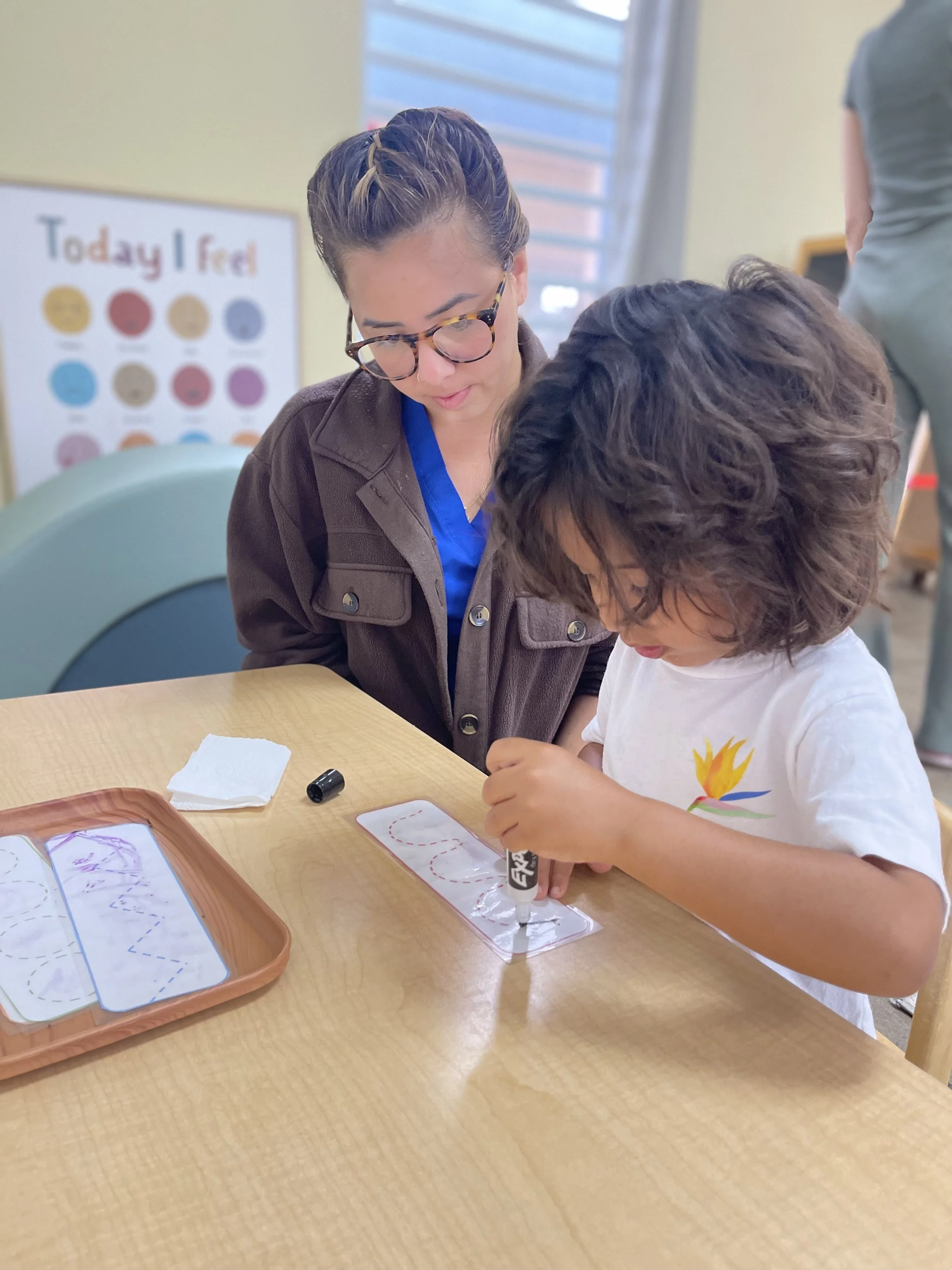 profesora obvservando a un niño escribiendo