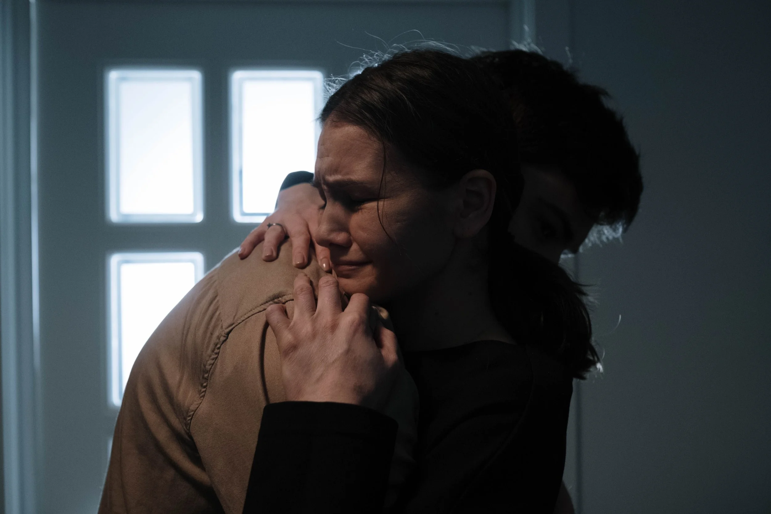 Woman being comforted by her partner during an emotional moment, illustrating support during postpartum mental health struggles
