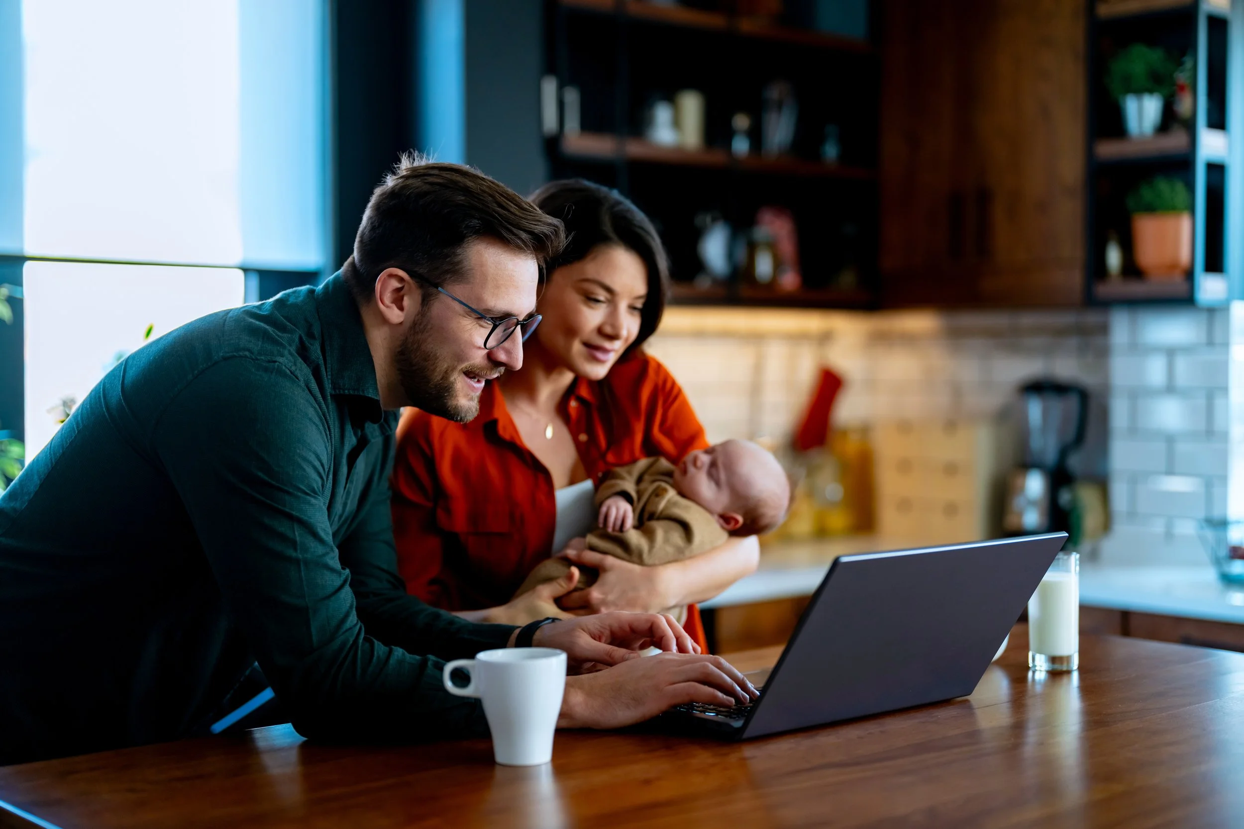 Couple in kitchen looking for postpartum therapy on laptop together