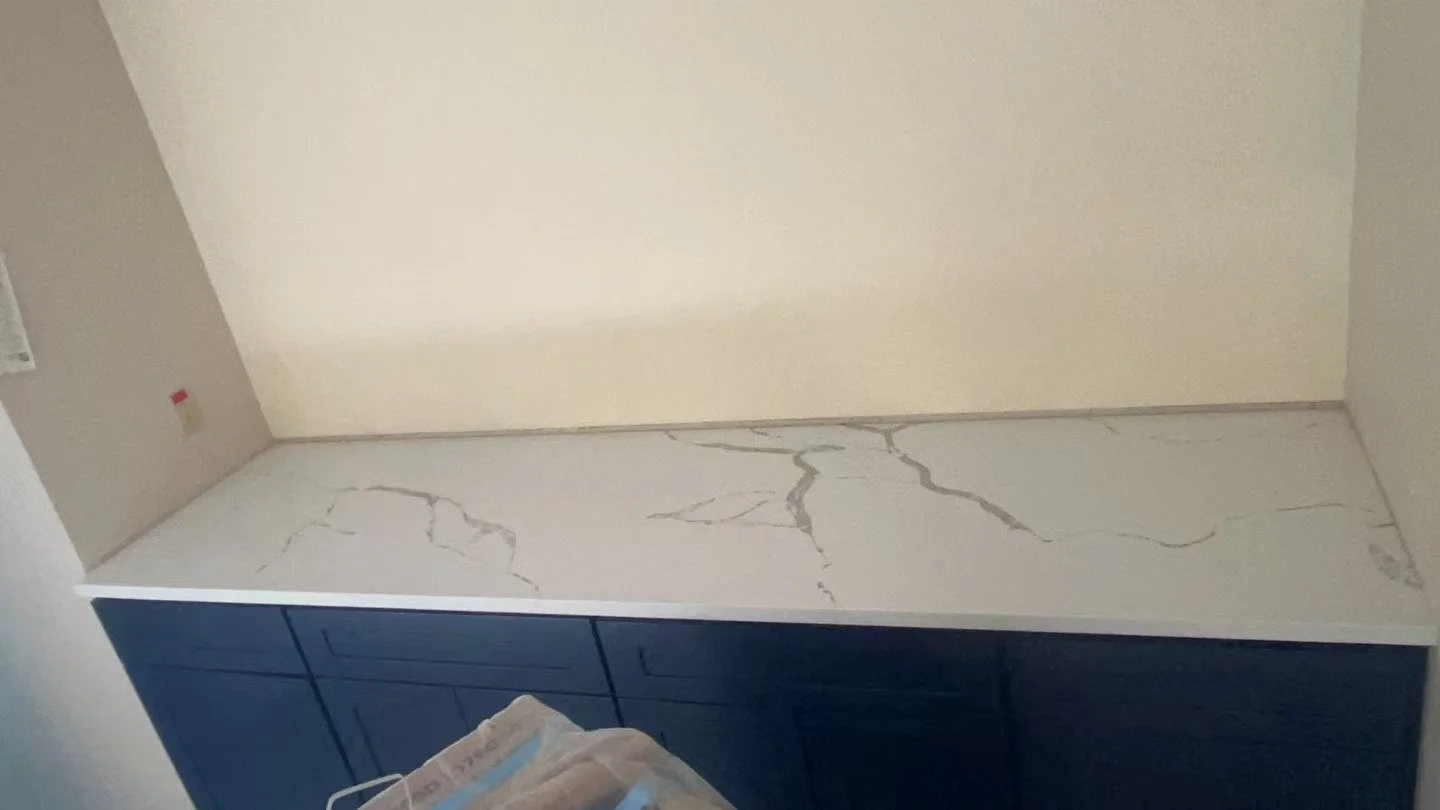 A kitchen counter with a white marble surface and blue cabinets underneath.