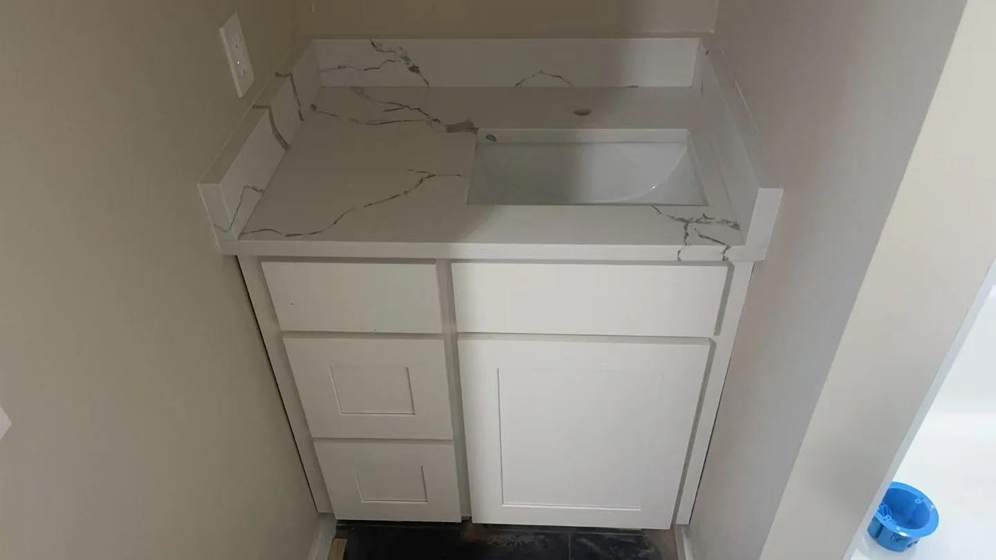 Small bathroom vanity with a white cabinet and marble-look countertop, in a bathroom with light-colored walls.