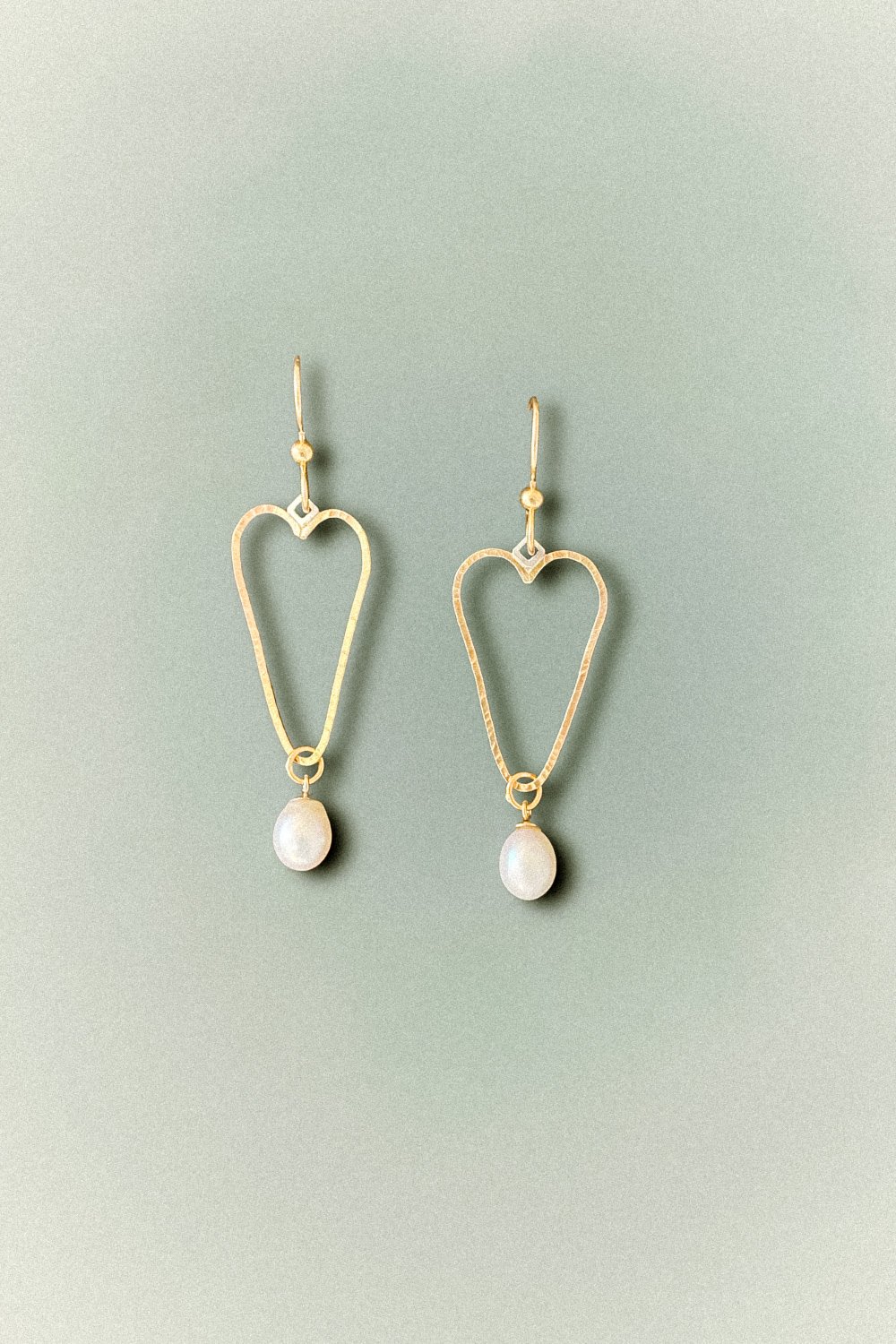 Elegant Golden Hearts Pearl Earrings featuring hammered gold-filled hearts paired with large, lustrous pearls, handcrafted in Linda Lewis's Avila Beach studio.