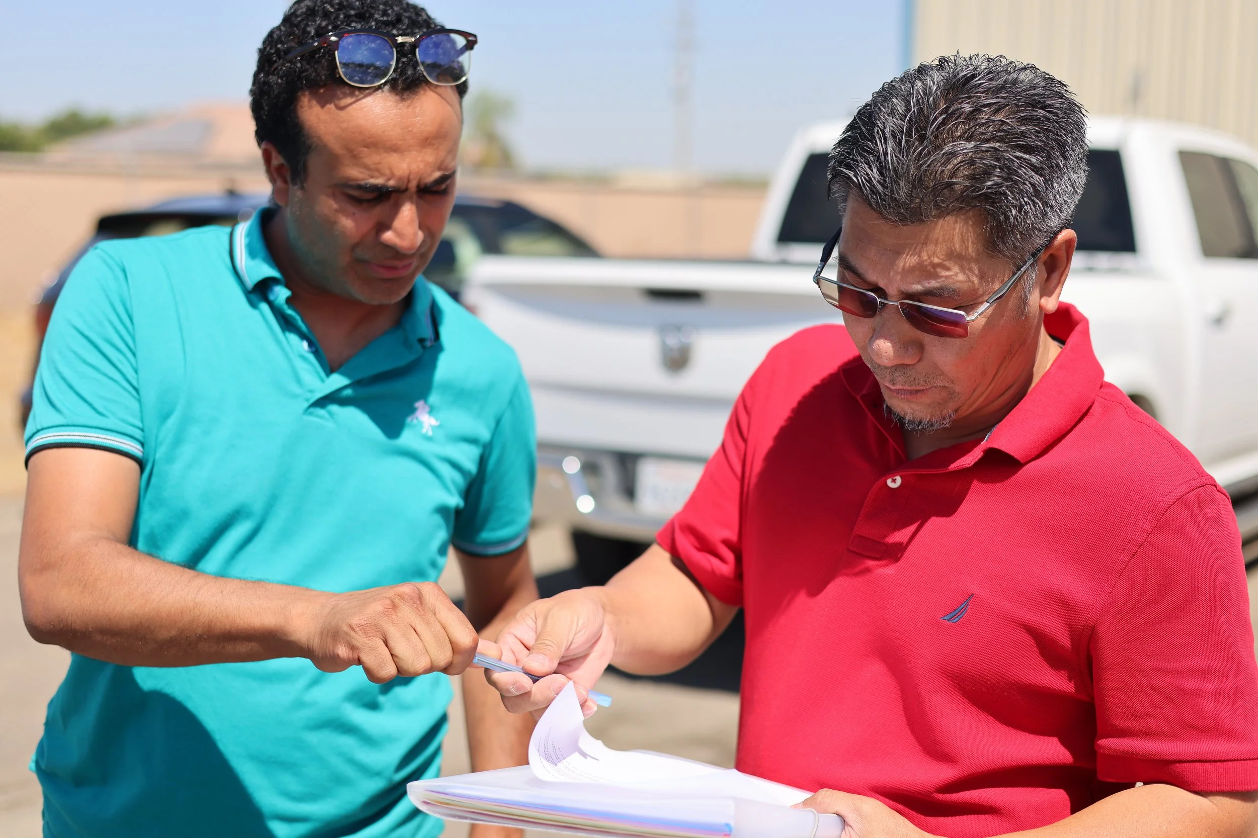 Two people reviewing documents together outdoors, emphasizing the collaborative planning and coordination involved in Saba Community Food Alliance's efforts to manage food distribution and support local farmers in the Bay Area