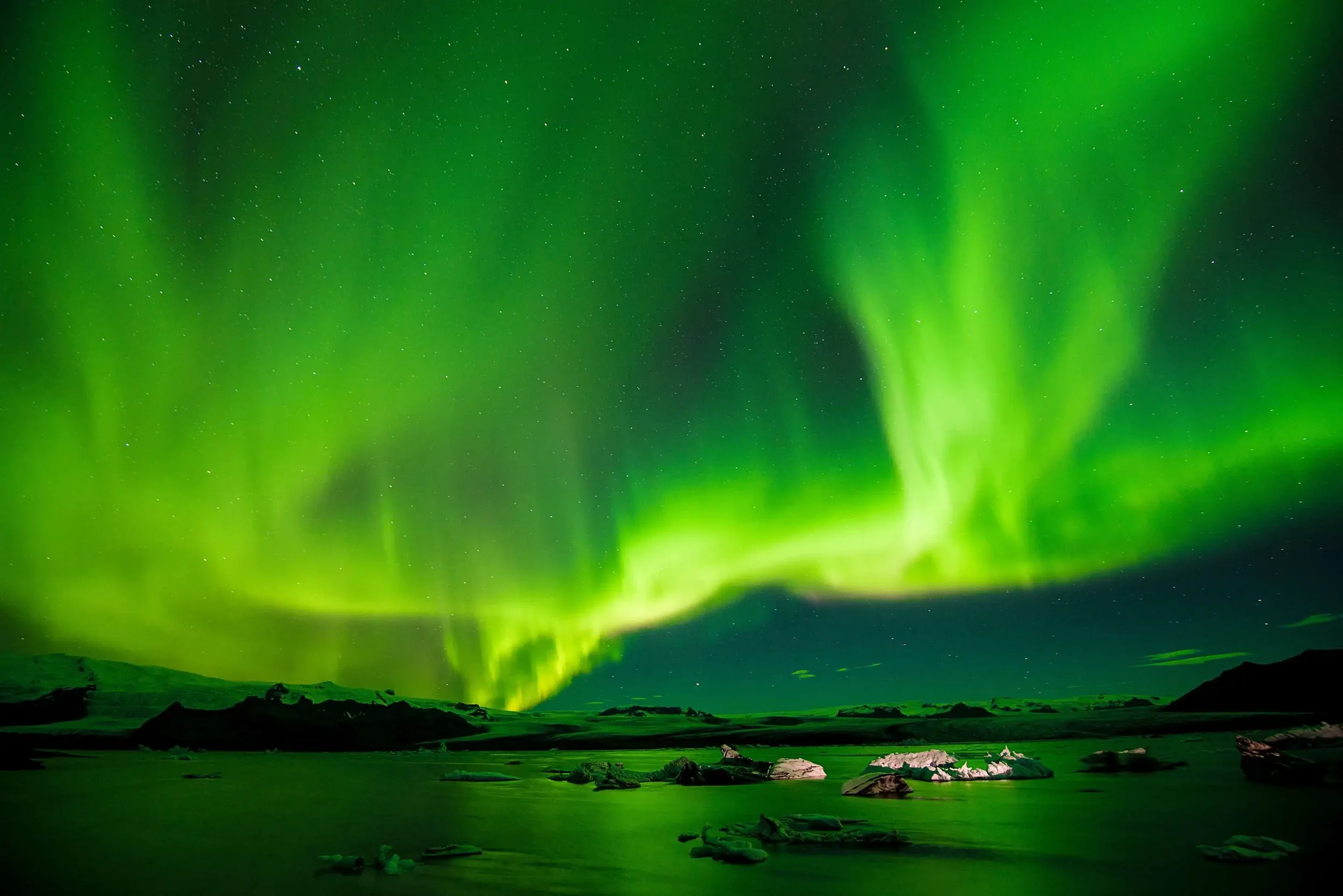Northern Lights over icy landscape during luxury adventure expedition with The Three’s Club