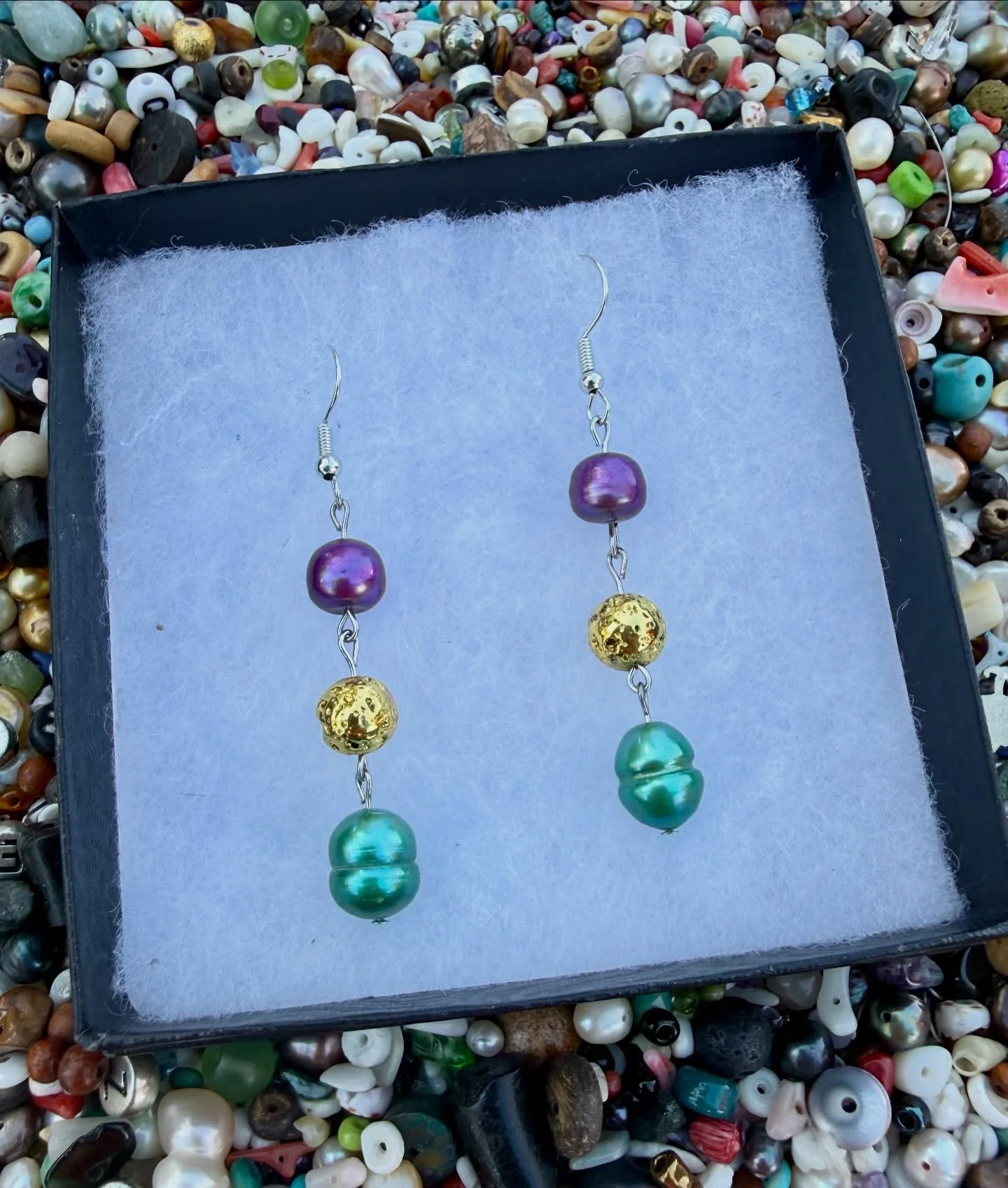 It&rsquo;s a beautiful day here @abitasprings.farmersmarket 

We decided to bring a little Mardi Gras Spirt 💜💚💛into our newest earrings. Made with pearls and metalized lava rock &hellip;a little shimmer, a little texture, and just enough bold to t