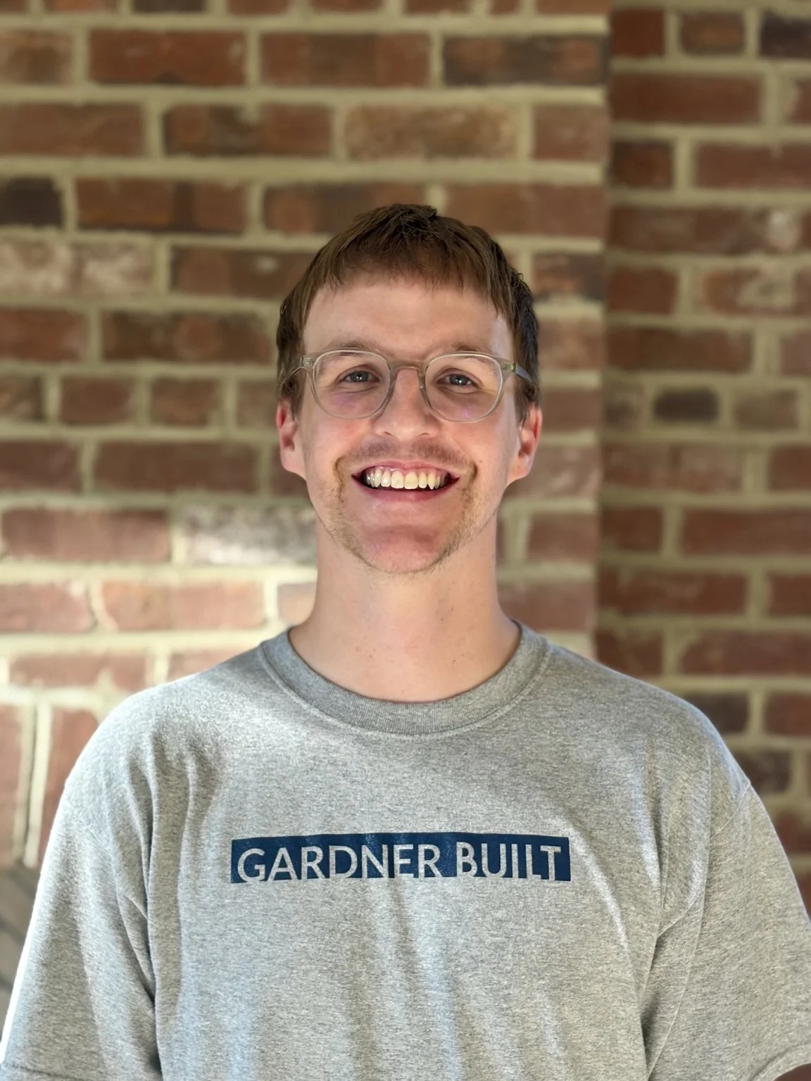 Brendan Murphy, carpenter at Gardner Construction, standing in front of a brick wall.