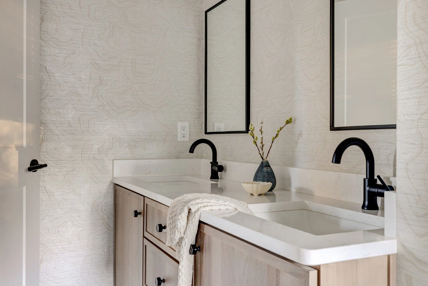 Inspired by natural tones but with a modern twist, this primary bath features a bold green tile that brings a fresh, grounded energy to the space. The rest of the design leans into simplicity &mdash; warm woods, soft textures, and a softly patterned 