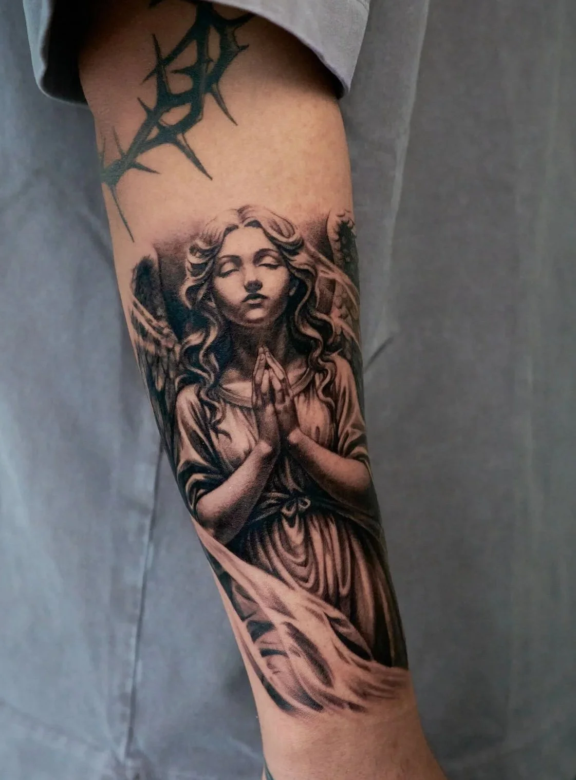Detailed black and gray angel sleeve by Harris at Recycle Tattoo. This custom piece features a praying angel with a hummingbird accent. Explore Harris’s illustrative portfolio at our Garden Grove studio.