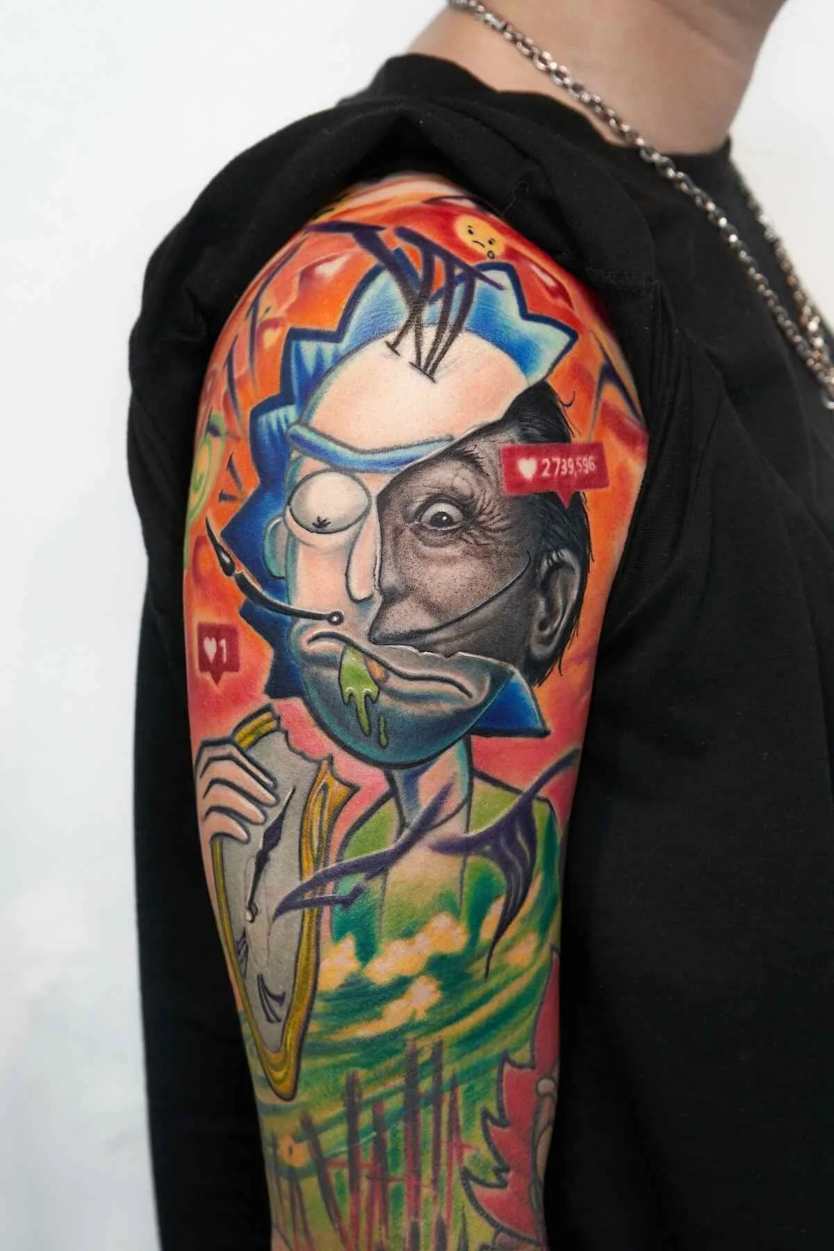 Bright, colorful tattoo sleeve on a person's upper arm, depicting a stylized cartoon face with exaggerated features, including a wide open mouth, sharp teeth, and a cigarette. The tattoo features vibrant hues of orange, yellow, green, blue, and black