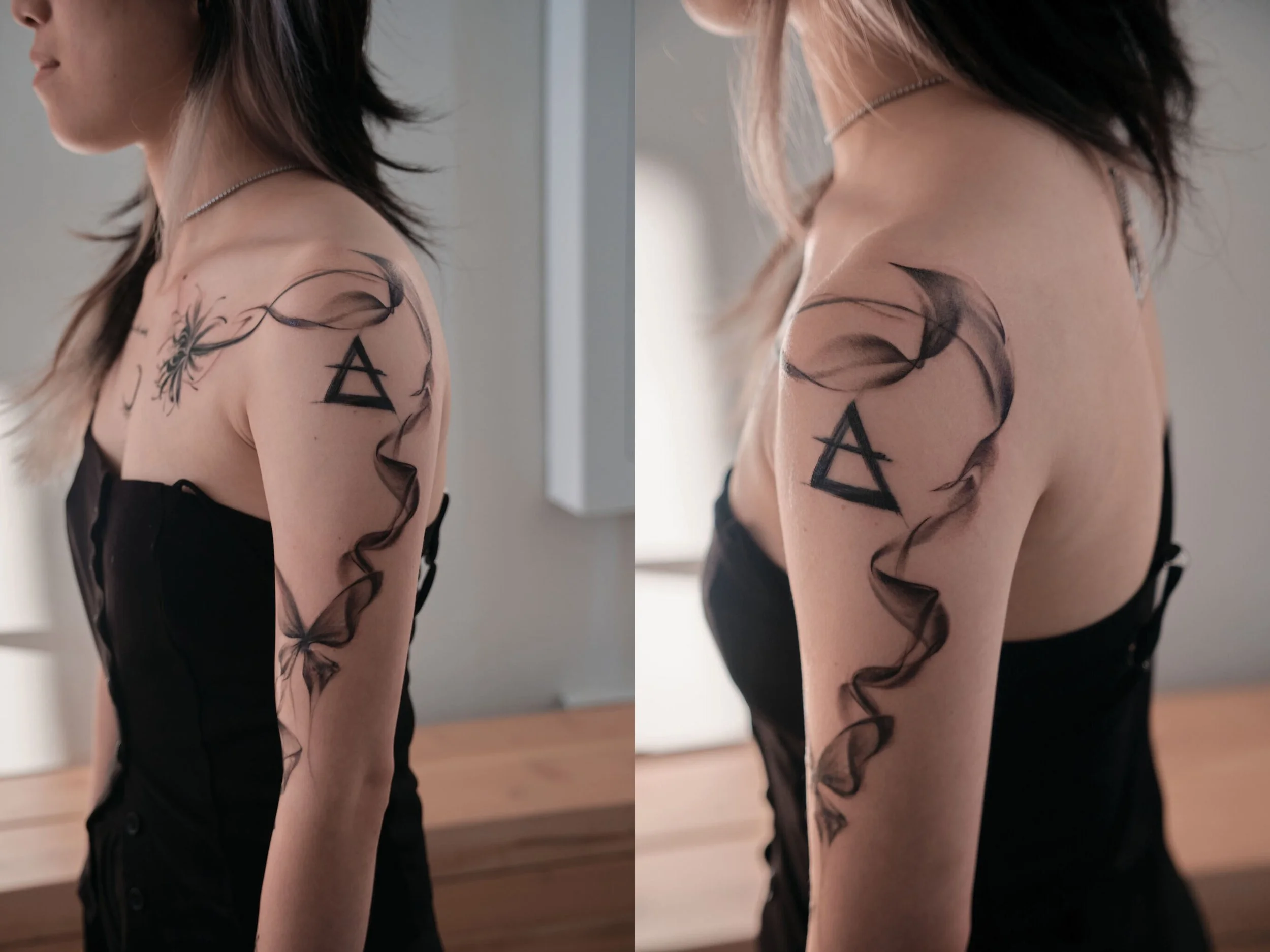 A woman with shoulder-length hair, wearing a black strapless dress, shows a tattoo on her upper arm and shoulder. The tattoo includes a geometric triangle symbol and black ink flowing designs.